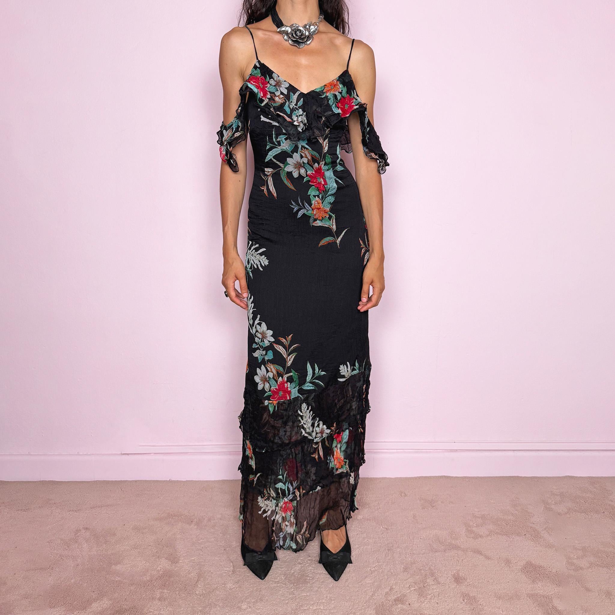 Vintage 2000s Guess Los Angeles black floral maxi dress with a romantic off-shoulder silhouette, delicate adjustable spaghetti straps, and dramatic ruffle detailing across the bust and sleeves. Designed with a fitted body, side zip closure, softly flared maxi skirt, and sheer textured floral panels through the hem. A dreamy statement evening dress, perfect for summer occasions.