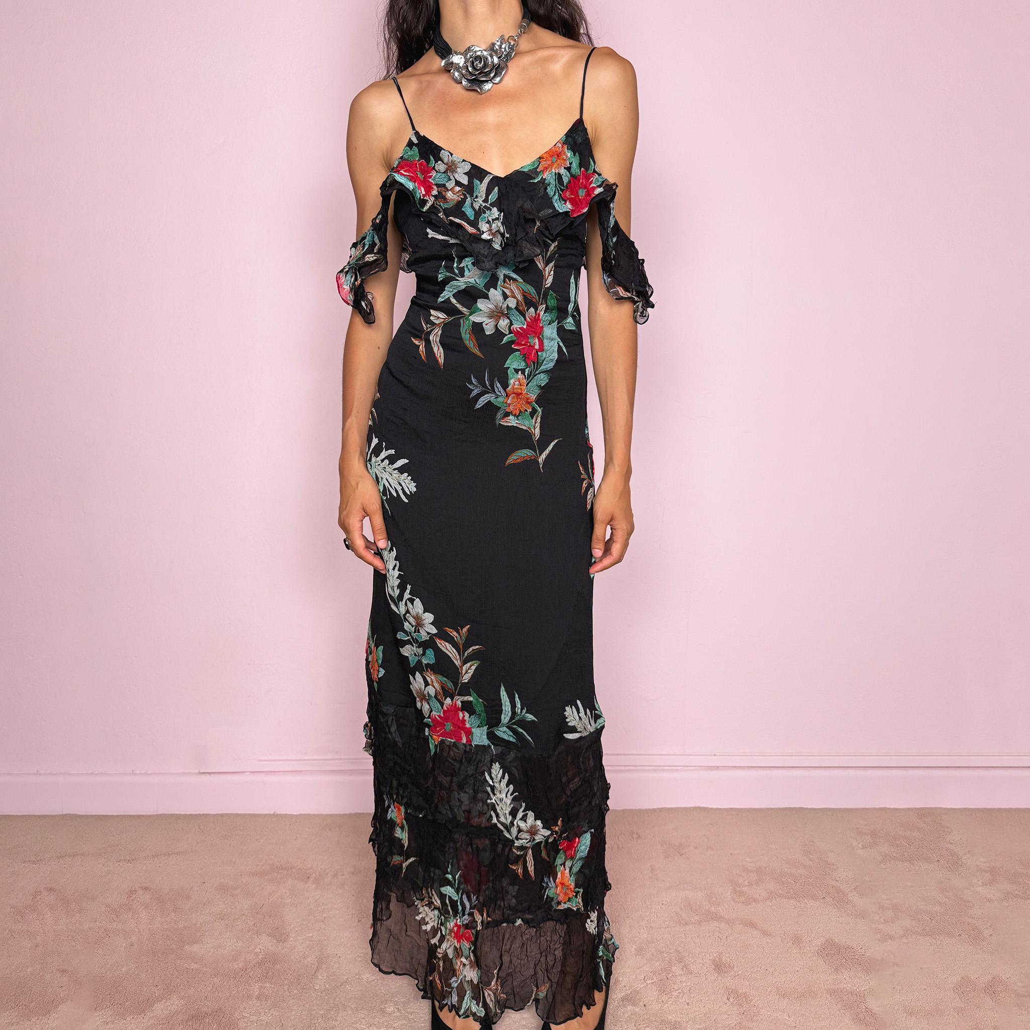 Vintage 2000s Guess Los Angeles black floral maxi dress with a romantic off-shoulder silhouette, delicate adjustable spaghetti straps, and dramatic ruffle detailing across the bust and sleeves. Designed with a fitted body, side zip closure, softly flared maxi skirt, and sheer textured floral panels through the hem. A dreamy statement evening dress, perfect for summer occasions.