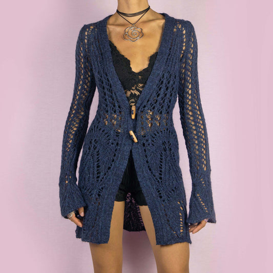 The Y2K Blue Long Crochet Cardigan is a vintage 2000s cardigan featuring a deep V-neckline and long, flared sleeves. Made from a wool blend, this longline cardigan is lightweight yet cozy, with wooden toggle button closures and a stretchy design. Perfect for layering over outfits in cooler weather.