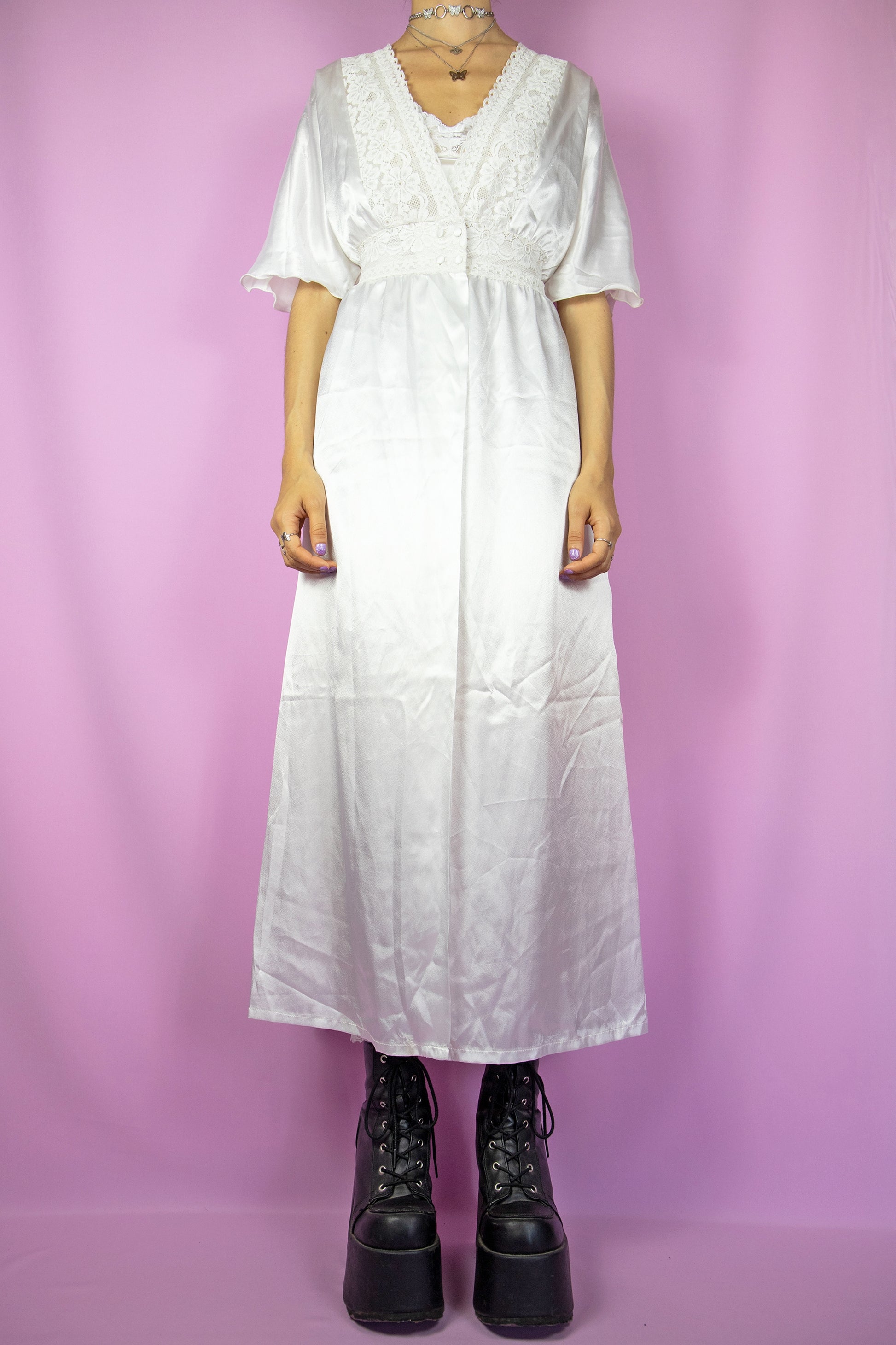The Vintage 90s White Satin Duster Jacket is a white short-sleeved maxi duster coat with a button closure at the waist and lace details. Romantic 1990s white lace peignoir robe.