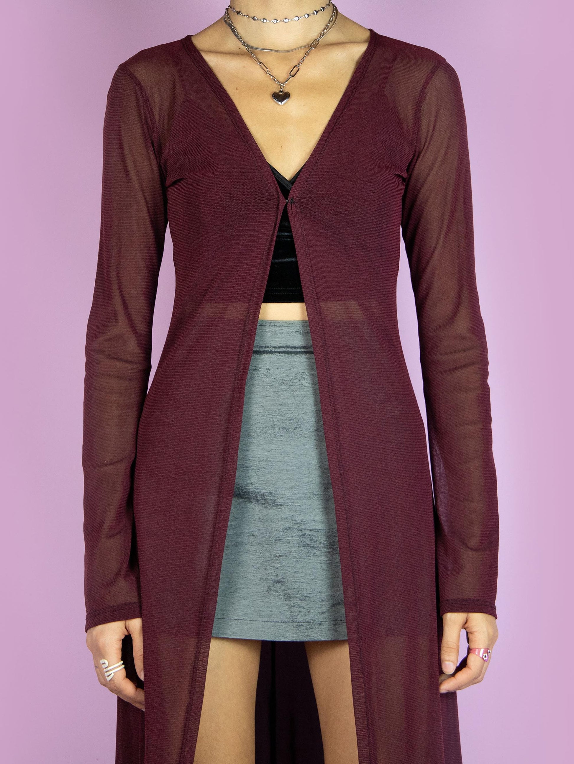 The Y2K Maroon Mesh Duster Jacket is a vintage 2000s cyber festival rave party style burgundy semi-sheer maxi long coat with bell sleeves and a front hook closure.