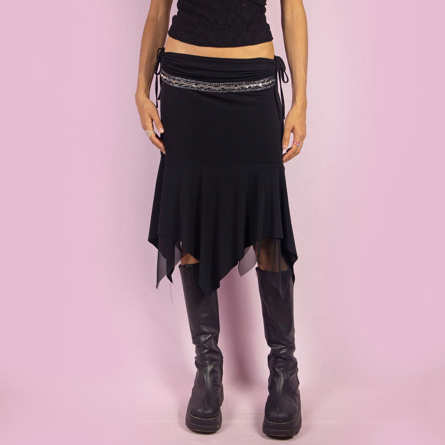 The Y2K Black Layered Asymmetric Skirt is a vintage 2000s piece featuring an avant-garde design. It has intricate bead detailing on the waist and adjustable ruched side ties. The skirt includes mesh sheer layers and a handkerchief-style asymmetric hemline, making it perfect for a bold night out look.