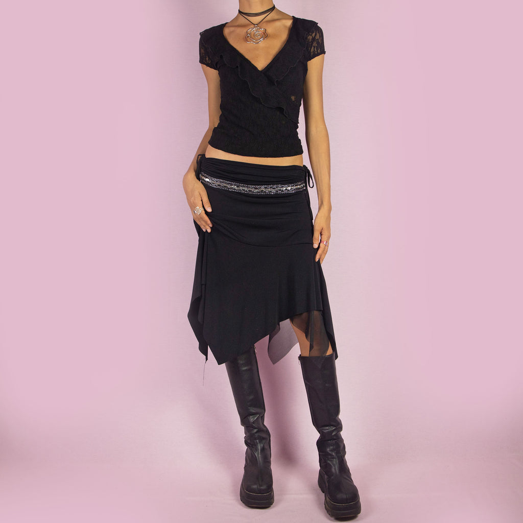 The Y2K Black Layered Asymmetric Skirt is a vintage 2000s piece featuring an avant-garde design. It has intricate bead detailing on the waist and adjustable ruched side ties. The skirt includes mesh sheer layers and a handkerchief-style asymmetric hemline, making it perfect for a bold night out look.