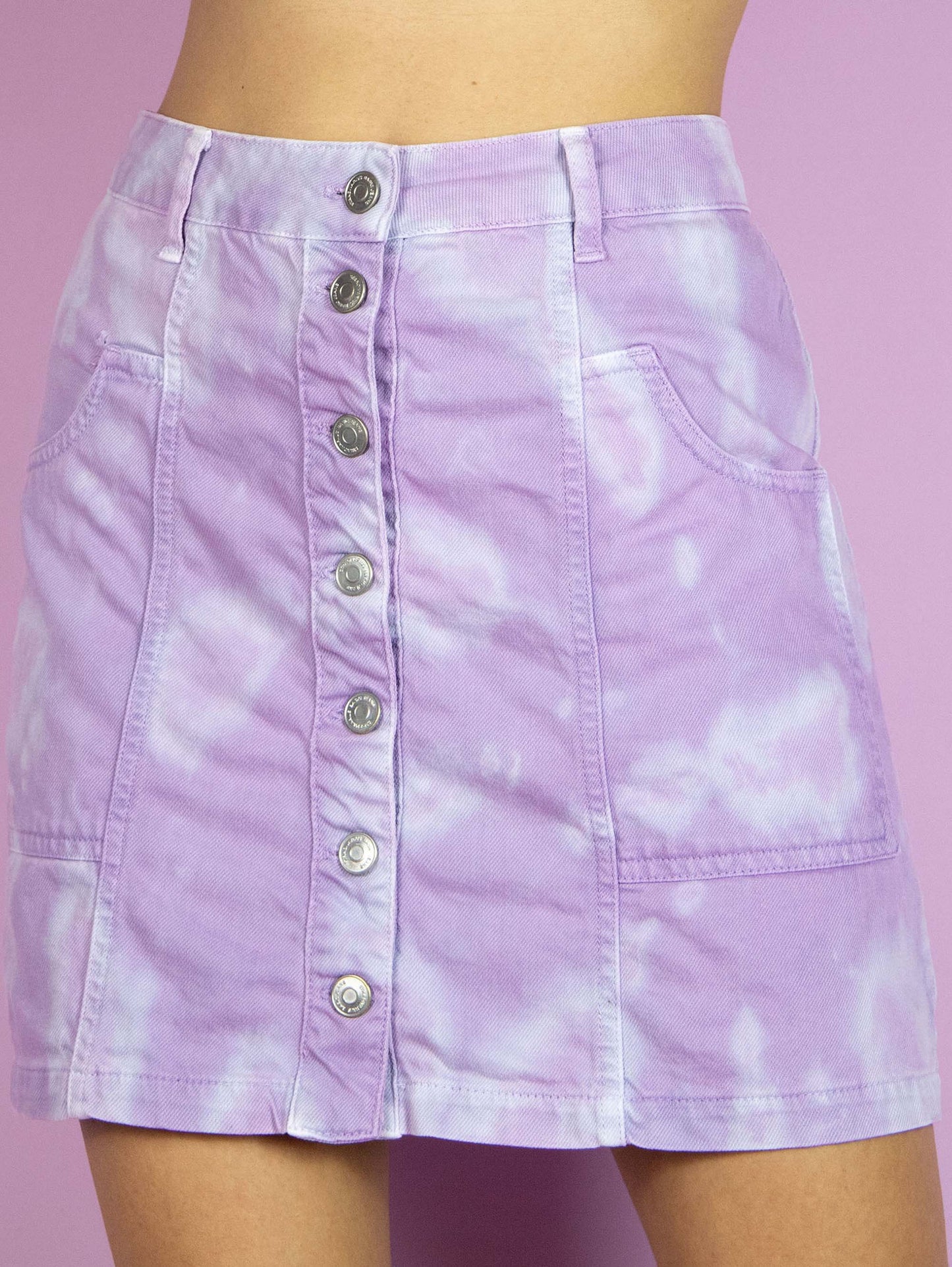 The Y2K Tie Dye Denim Mini Skirt is a vintage lilac and blue skirt with pockets and buttons. Cyber harajuku festival 2000s pastel purple bleached mini skirt.
