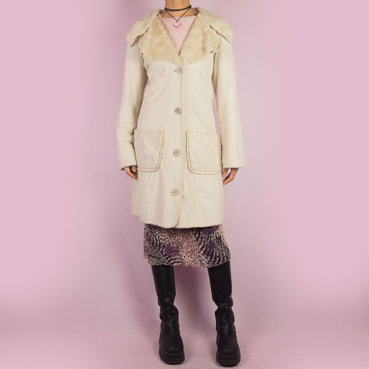 The Y2K Beige Faux Fur Overcoat is a vintage 2000s faux suede longline coat featuring a cozy faux fur collar and trim, large front patch pockets and button closures. Ideal for layering in the winter and any comfy fall outfit.