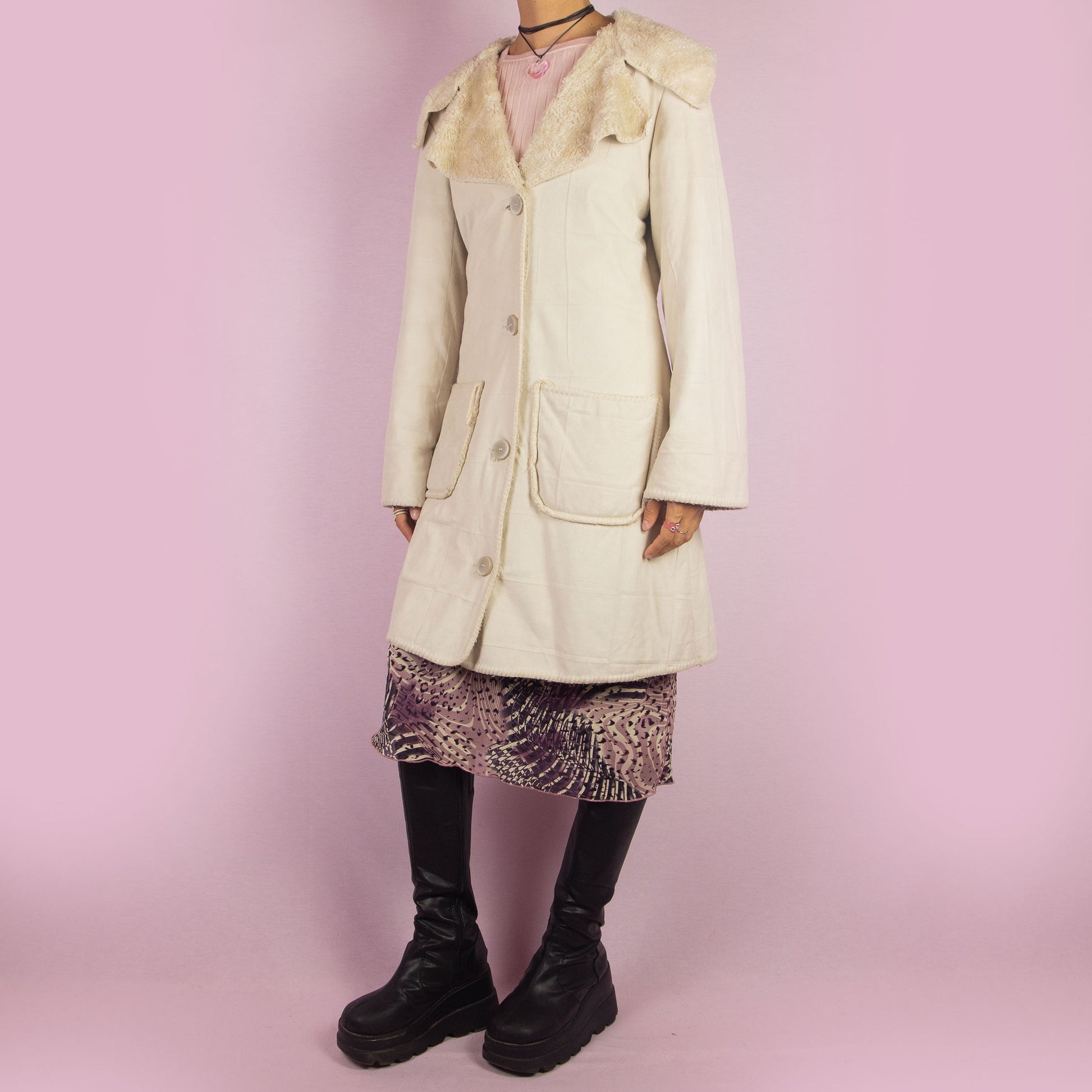 The Y2K Beige Faux Fur Overcoat is a vintage 2000s faux suede longline coat featuring a cozy faux fur collar and trim, large front patch pockets and button closures. Ideal for layering in the winter and any comfy fall outfit.