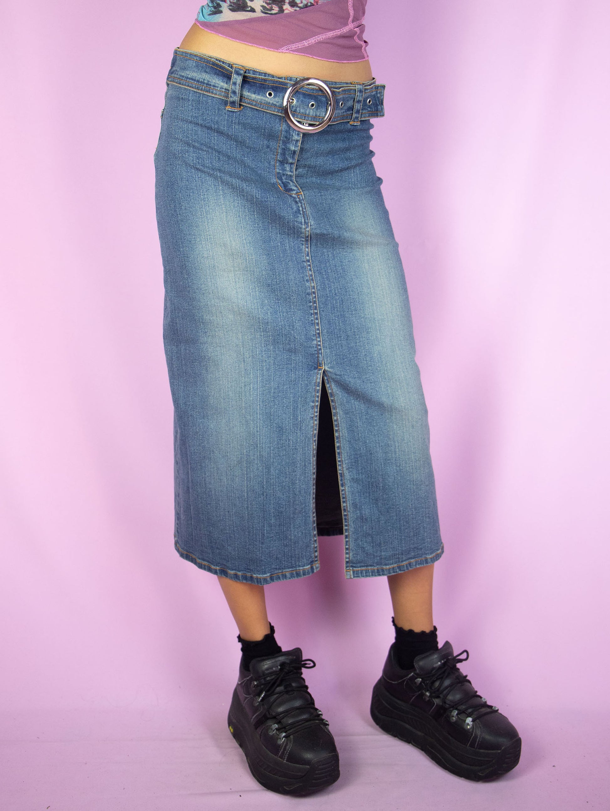The Y2K Denim Midi Skirt is a vintage 2000s cyber grunge inspired stretchy jean maxi skirt with a front slit, belt buckle and zipper closure.