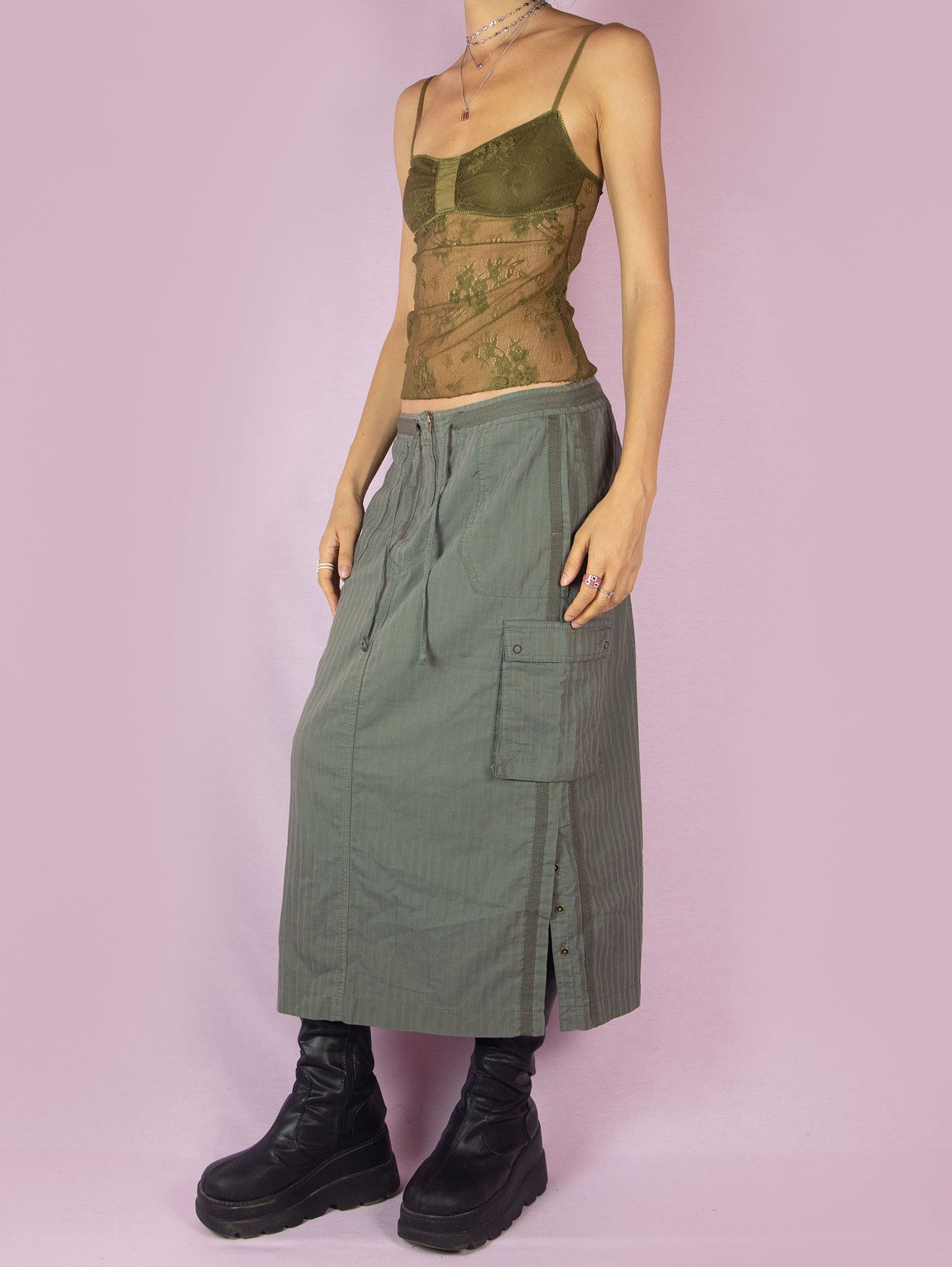 The Y2K Khaki Cargo Midi Skirt is a subversive grunge sporty utility vintage 2000s green striped skirt with pockets, front zipper closure, and side slits with snap buttons.