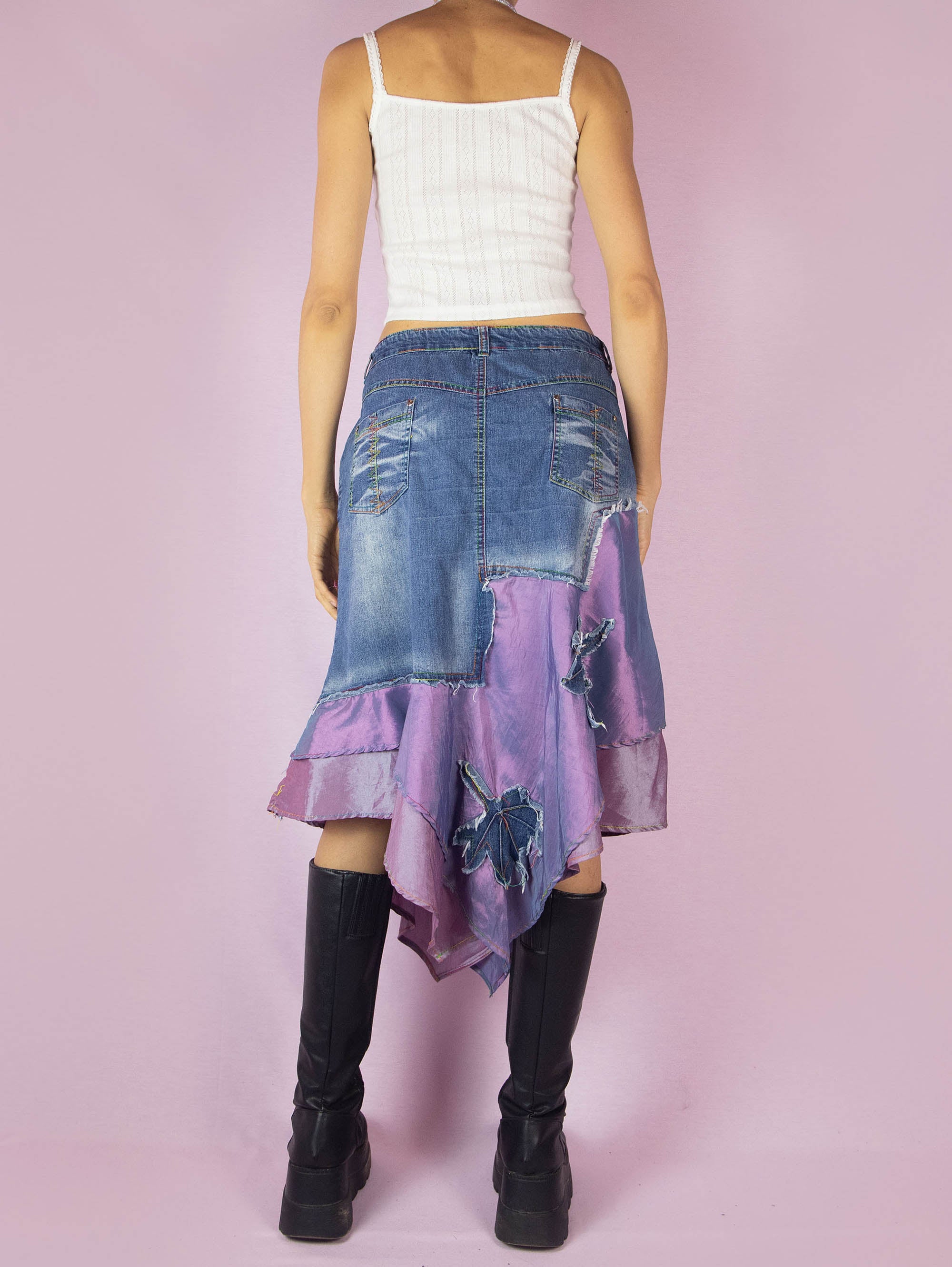 The Y2K Denim Asymmetric Trumpet Skirt is a vintage 2000s slightly stretchy jean midi skirt, avant-garde and deconstructed, with applique and acid wash details, a layered pointed hem, pockets, and a zipper closure.
