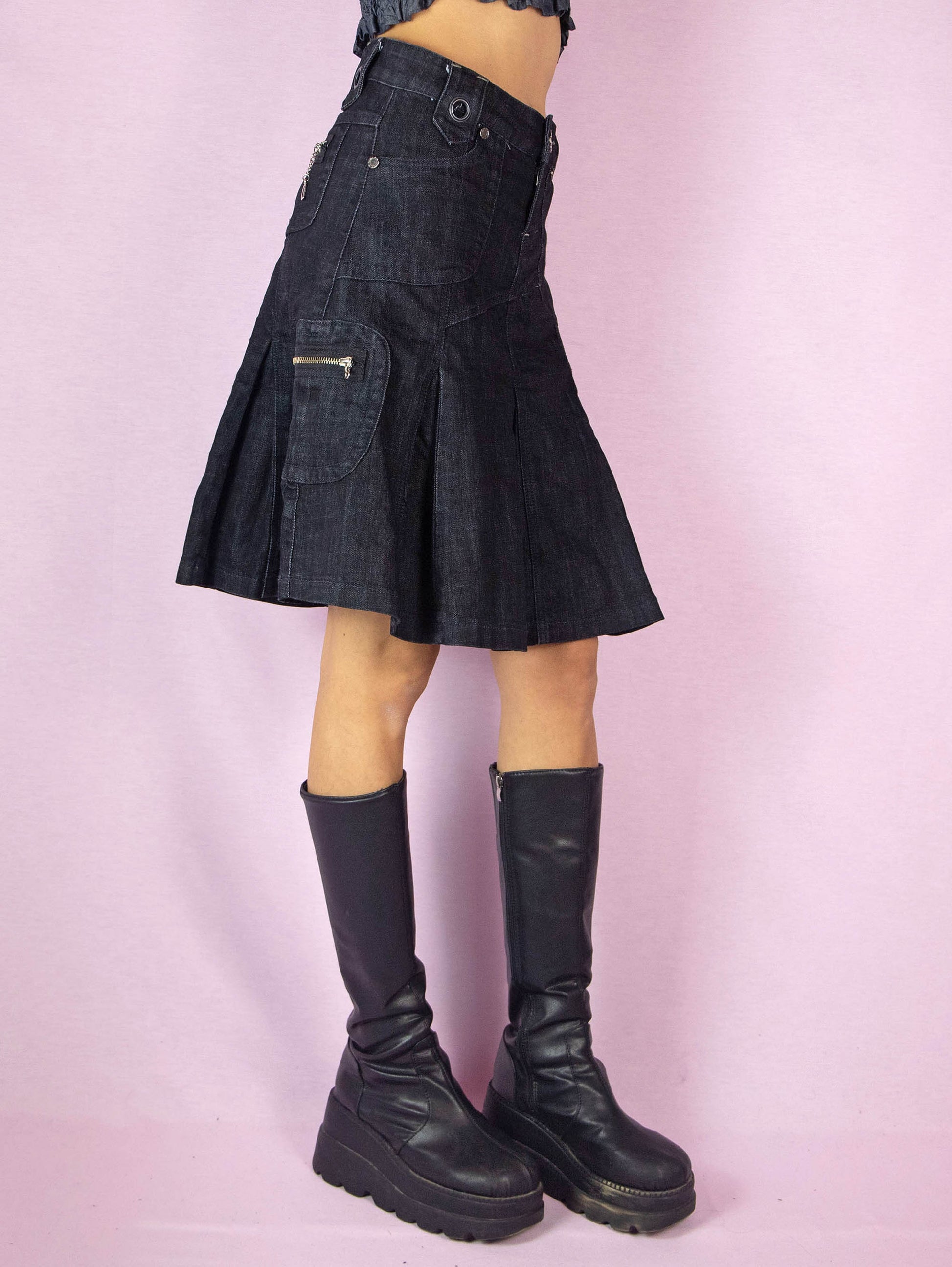 The Y2K Dark Denim Pleated Skirt is a nearly black vintage 2000s subversive grunge cargo-style A-line jean mini skirt with pockets and a front zipper closure.