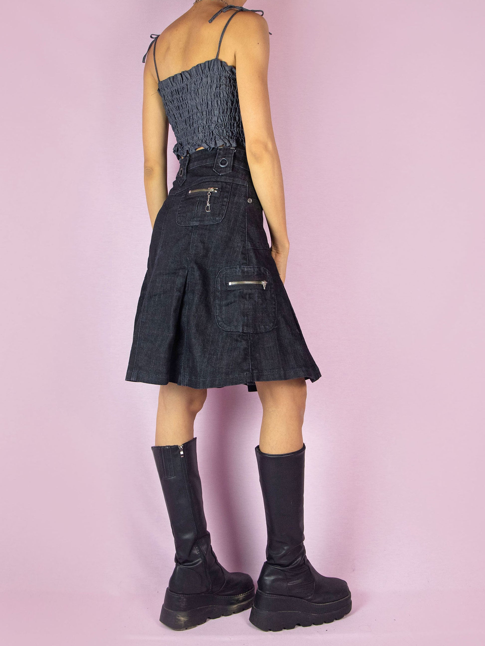 The Y2K Dark Denim Pleated Skirt is a nearly black vintage 2000s subversive grunge cargo-style A-line jean mini skirt with pockets and a front zipper closure.
