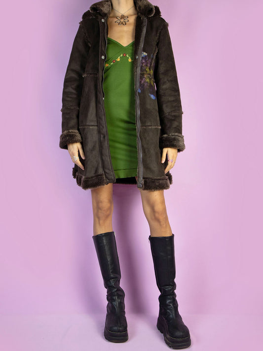 The Y2K Dark Brown Penny Lane Coat is a vintage 2000s boho-inspired, suede-style jacket featuring faux fur trim on the cuffs, collar, and hem. Adorned with a floral painted detail on the front and equipped with a hood, this whimsical coat also includes a zipper closure and a faux fur lining. Perfect for a cozy casual winter outfit.