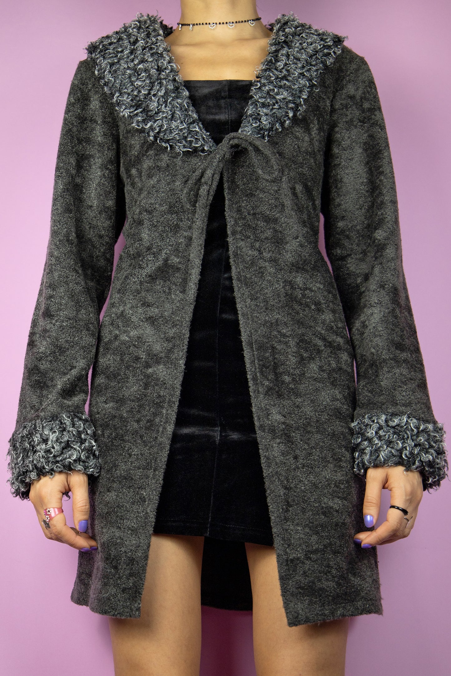 The Y2K Gray Faux Fur Duster Jacket is a vintage 2000s piece inspired by the iconic Penny Lane style, featuring a cozy textured fabric in a deep charcoal gray, an open-front design with a tie closure and a faux fur trim along the collar and cuffs, adding a touch of whimsy. Perfect for evening parties and formal occasions.