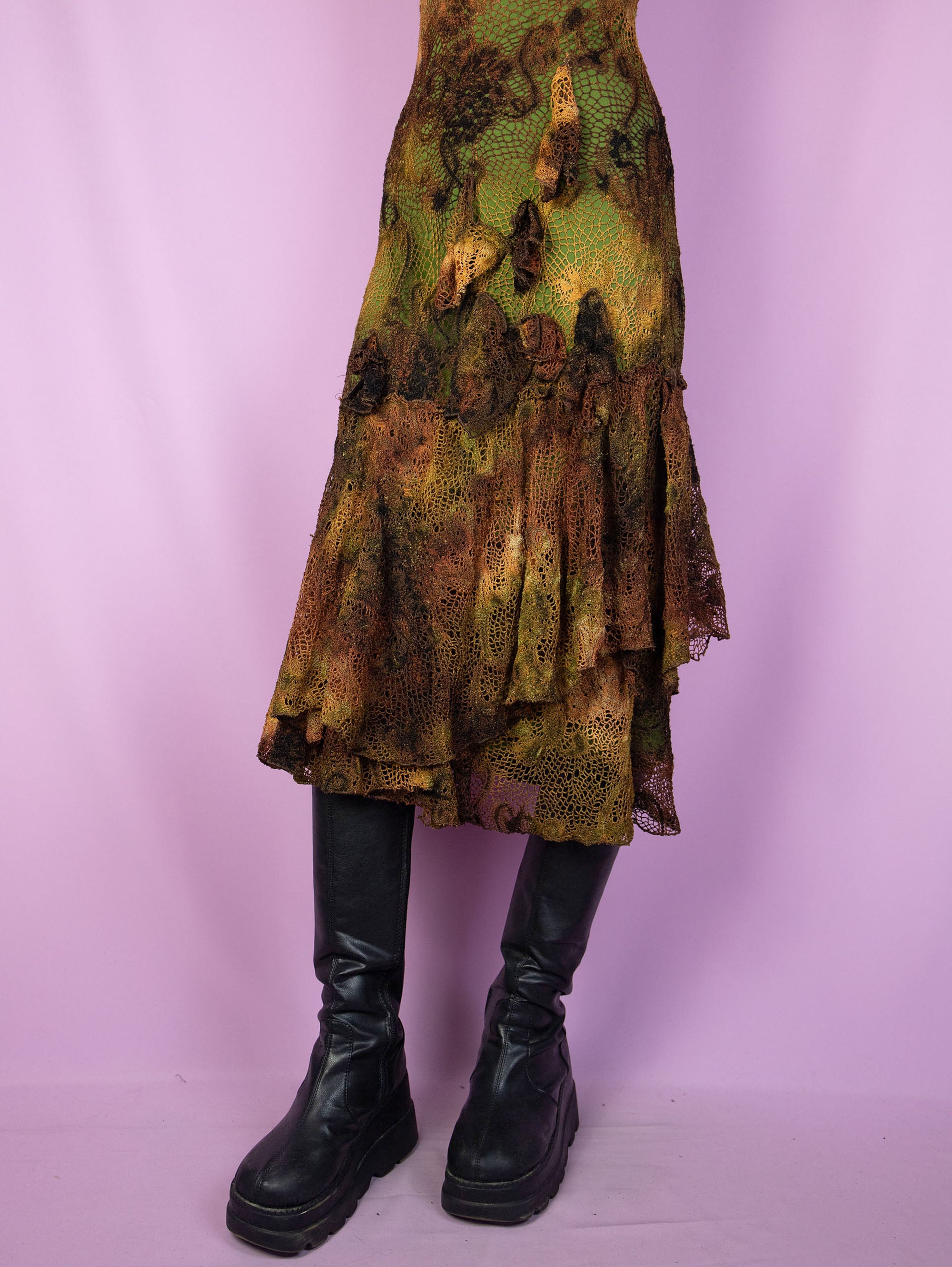 The Y2K Fairy Brown Midi Dress is a vintage sleeveless crochet-style mesh dress with a tie-dye pattern and a green lining. It features a layered ruffled hem, and a charming asymmetric design. Romantic avant-garde 2000s evening party dress.