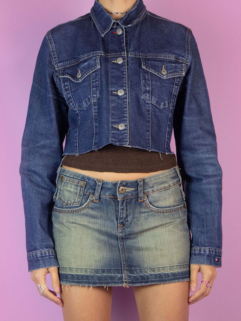 The Y2K Denim Cropped Jacket is a vintage 2000s jean jacket featuring a classic blue denim wash. It has a button-front closure, chest pockets with flaps, and a raw hem. Perfect for casual outfits.