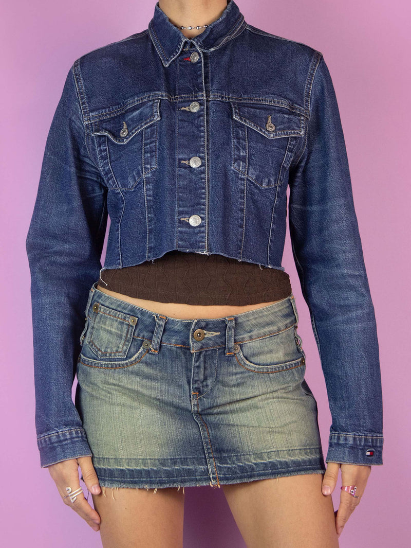 The Y2K Denim Cropped Jacket is a vintage 2000s jean jacket featuring a classic blue denim wash. It has a button-front closure, chest pockets with flaps, and a raw hem. Perfect for casual outfits.