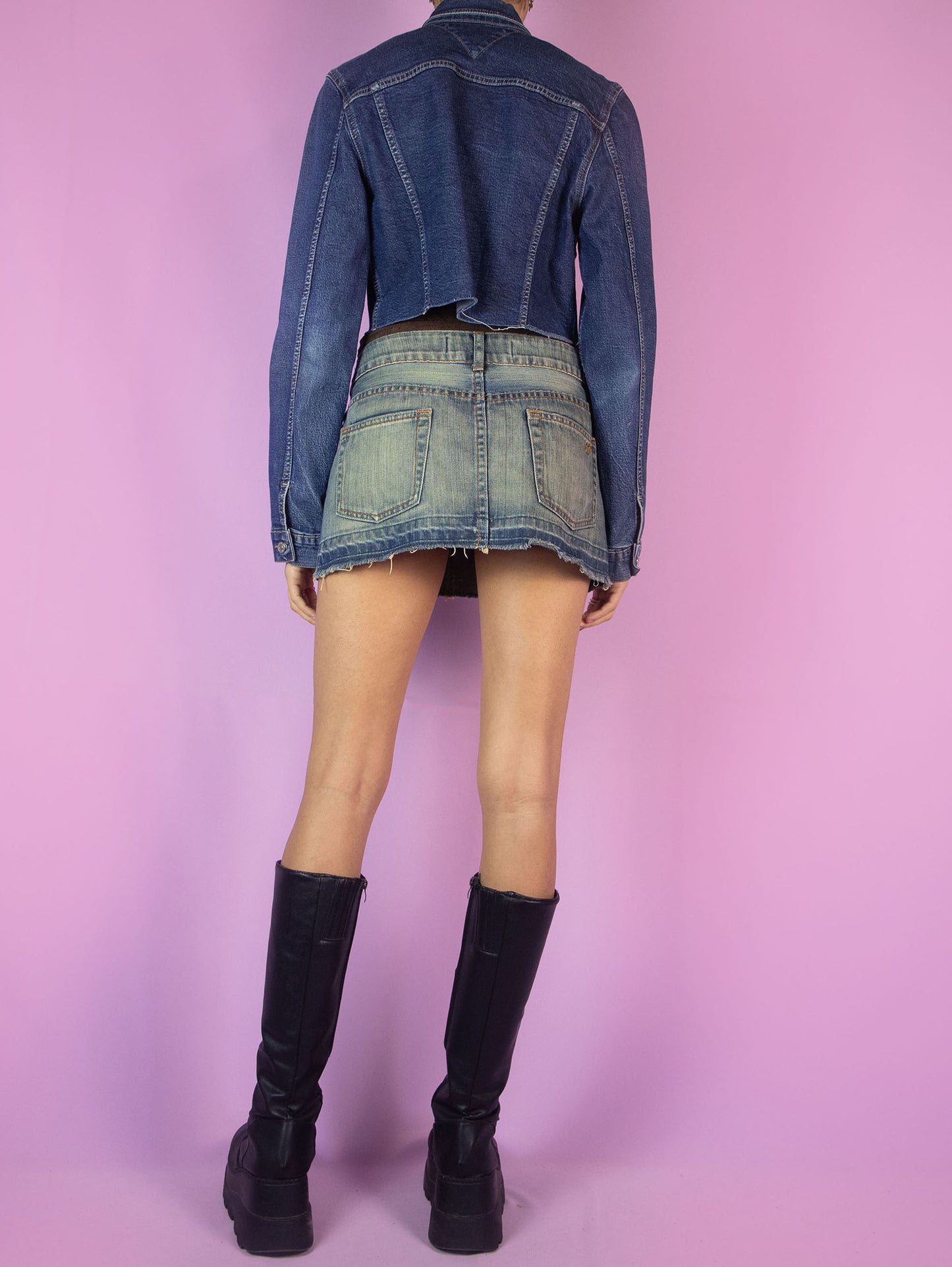 The Y2K Denim Cropped Jacket is a vintage blue denim jacket with collar, buttons, pockets, and a raw hem. Cyber grunge 2000s jean jacket.