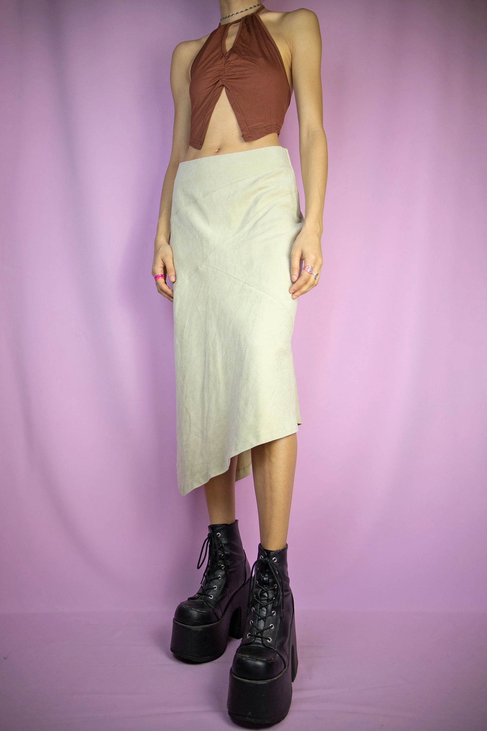 The Y2K Beige Asymmetric Midi Skirt is a vintage faux suede skirt with an asymmetrical pointed hem and a side zipper closure. Cyber fairy grunge 2000s boho maxi skirt.