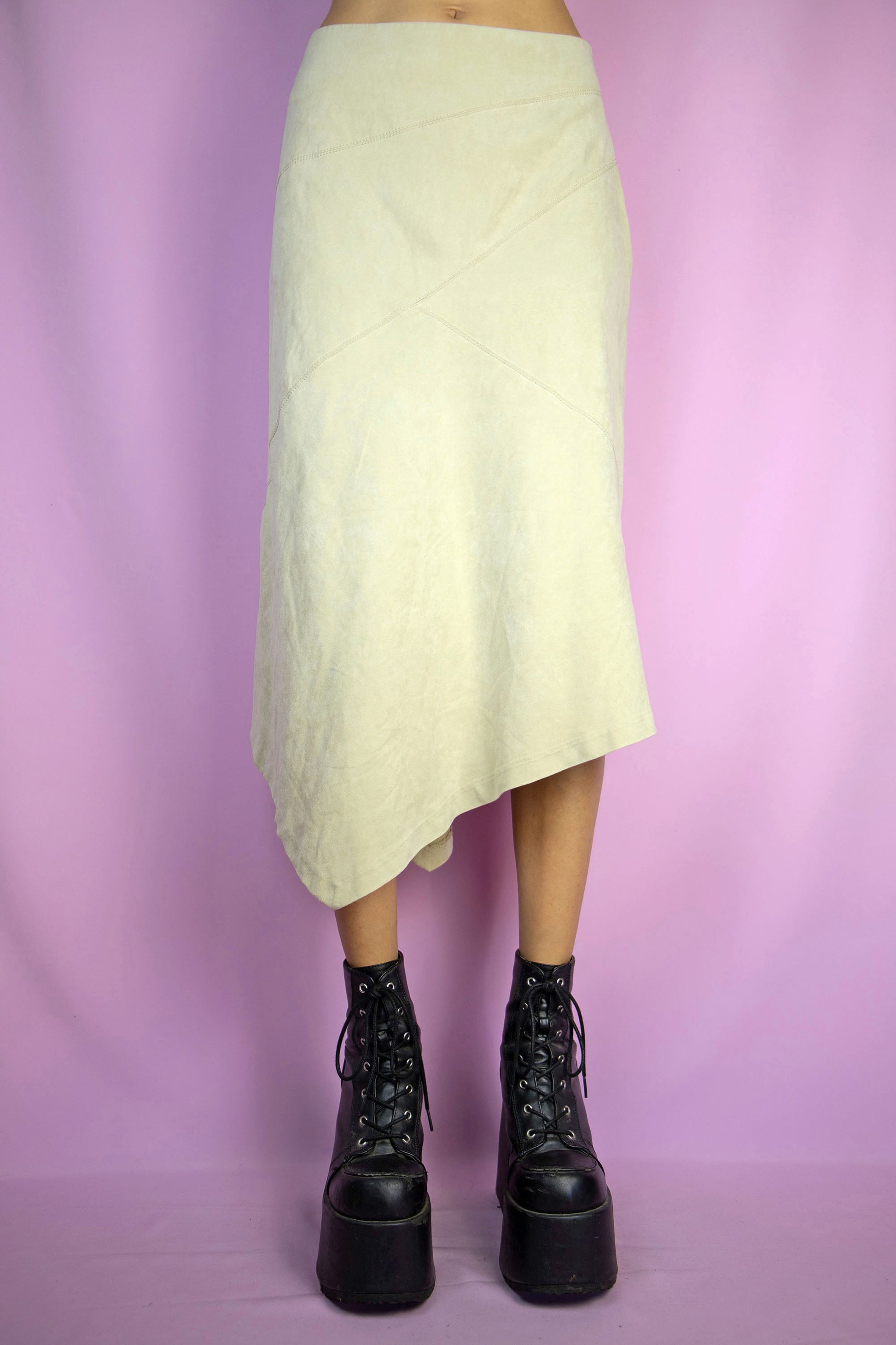 The Y2K Beige Asymmetric Midi Skirt is a vintage faux suede skirt with an asymmetrical pointed hem and a side zipper closure. Cyber fairy grunge 2000s boho maxi skirt.