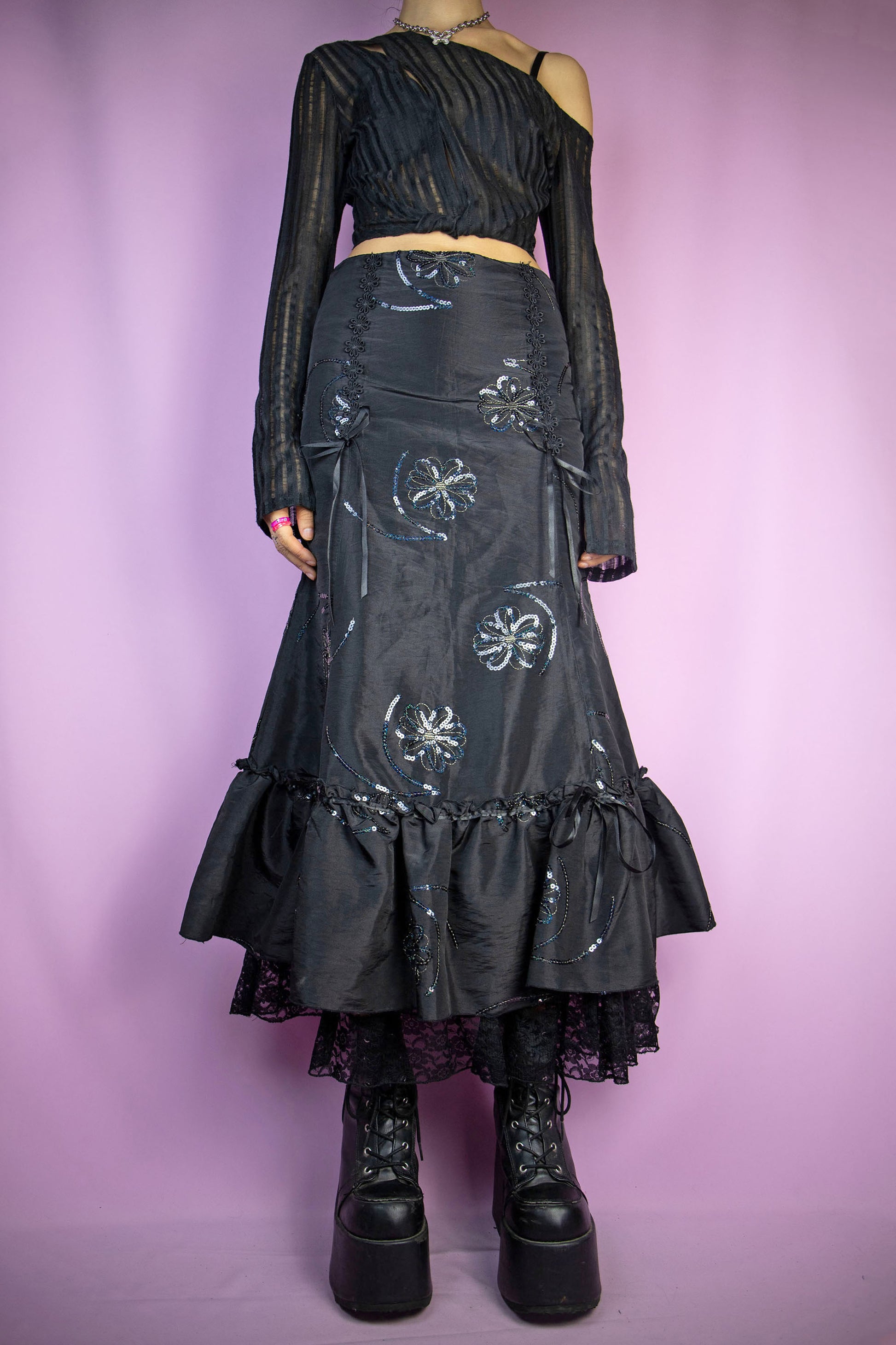 The Vintage 90s Black Trumpet Midi Skirt features a fitted waist that flares out into a trumpet silhouette, intricate sequin floral embroidery and ruffle lace details at the hem, and a side zipper closure. Perfect for a formal night party or elegant event. Excellent vintage condition.
