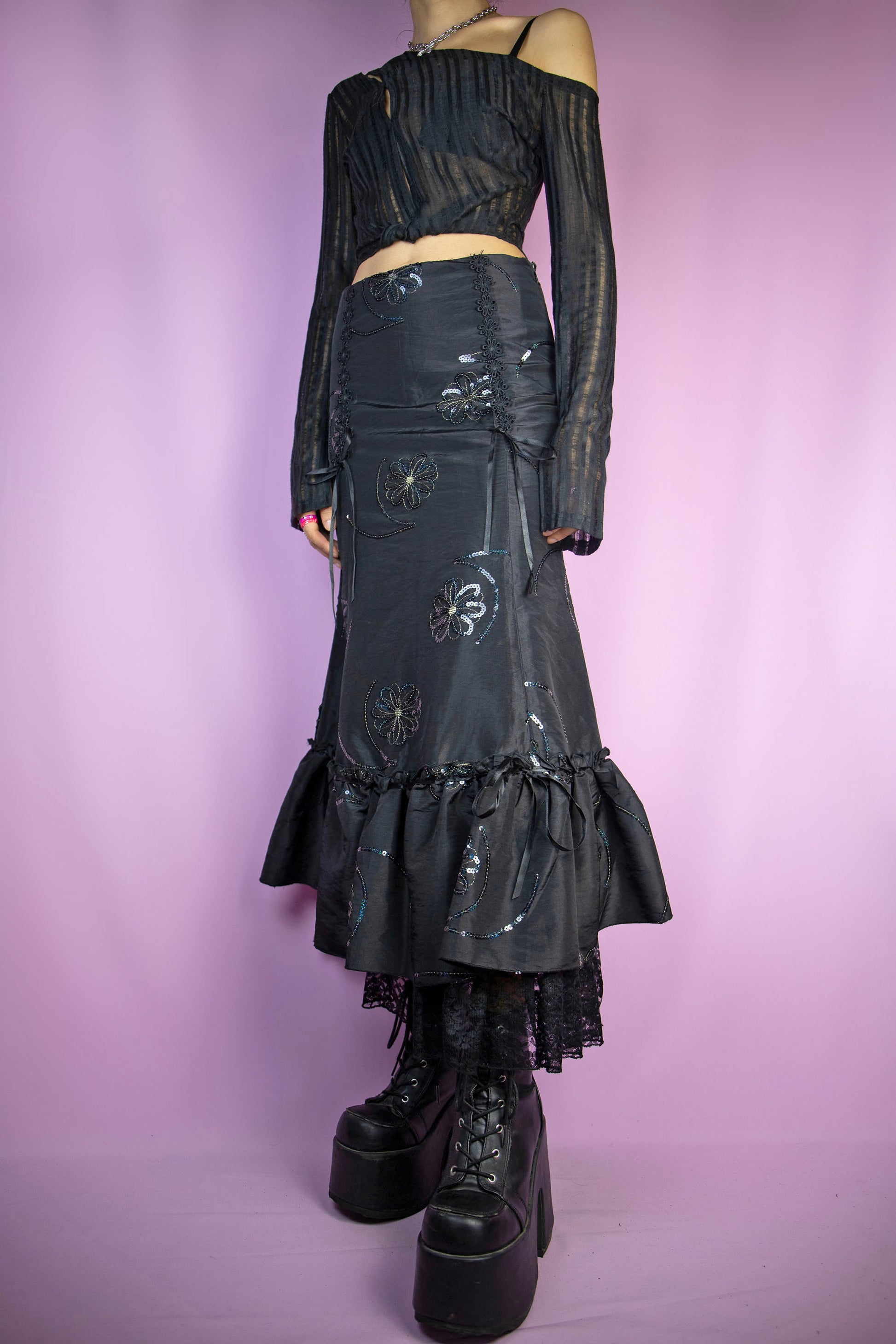 The Vintage 90s Black Trumpet Midi Skirt features a fitted waist that flares out into a trumpet silhouette, intricate sequin floral embroidery and ruffle lace details at the hem, and a side zipper closure. Perfect for a formal night party or elegant event. Excellent vintage condition.