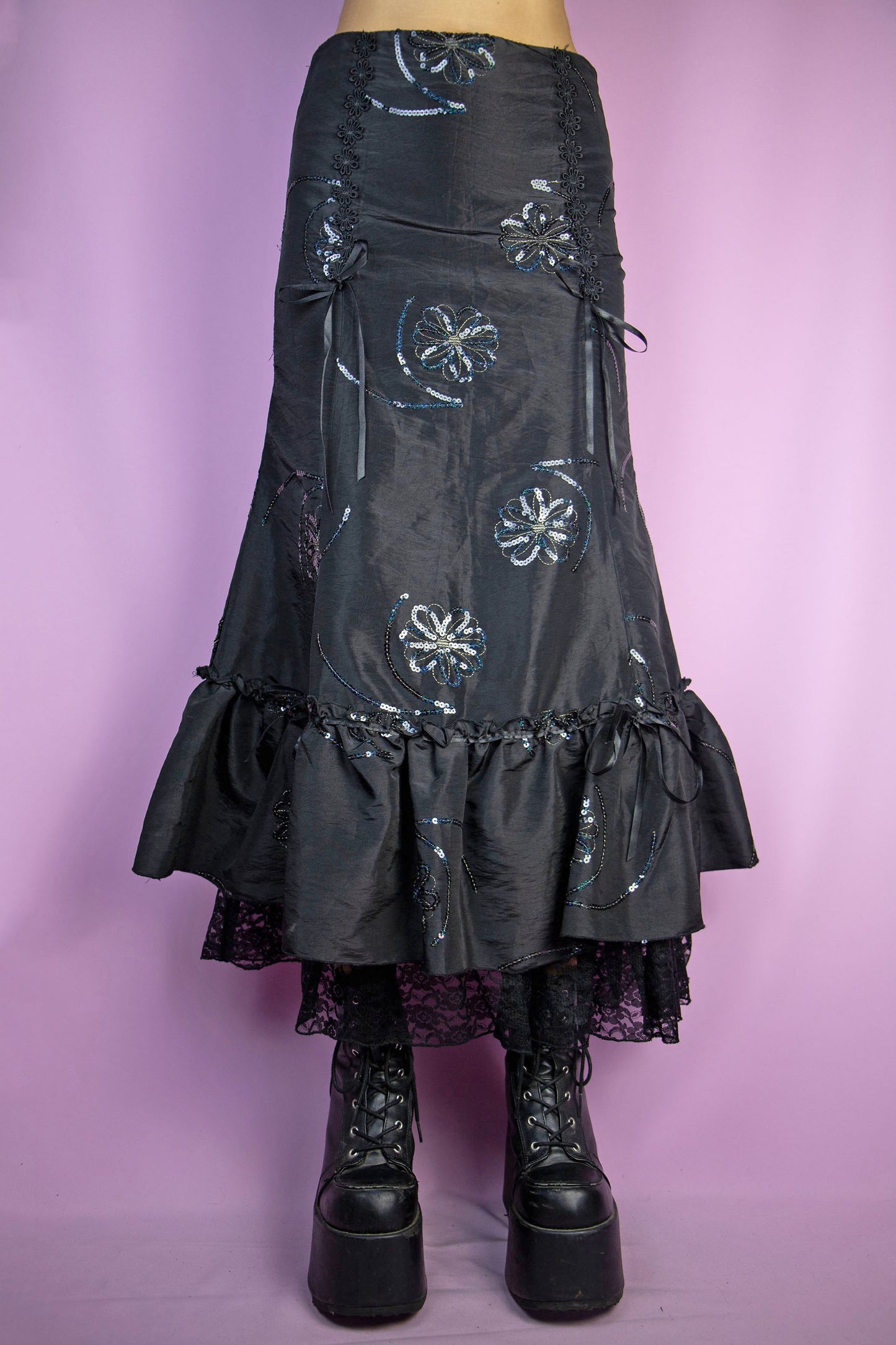 The Vintage 90s Black Trumpet Midi Skirt is an embellished skirt adorned with sequin details, bows, a ruffled hem, and a side zipper closure. Elegant fairy goth 1990s evening party maxi skirt.