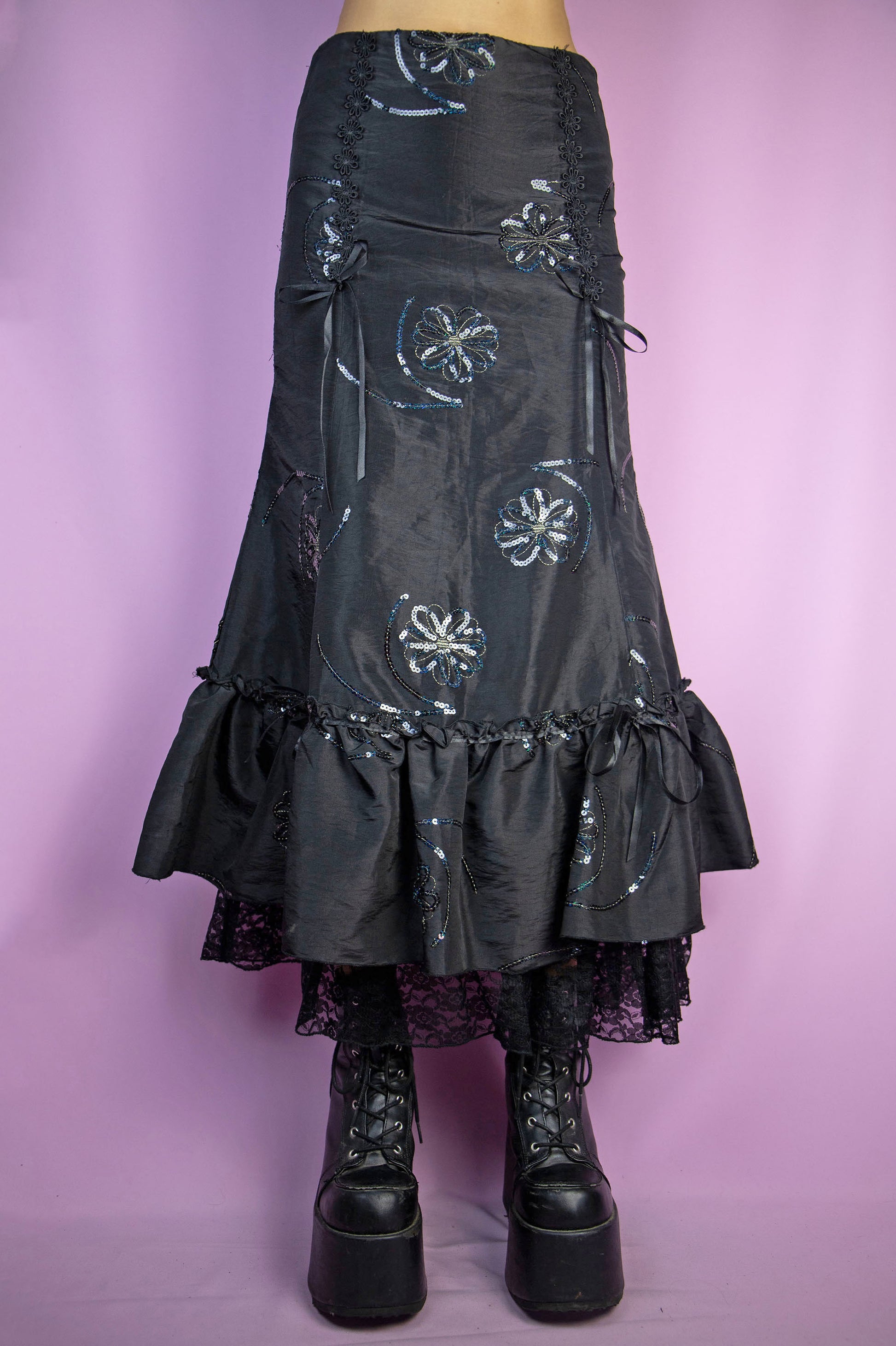 The Vintage 90s Black Trumpet Midi Skirt is an embellished skirt adorned with sequin details, bows, a ruffled hem, and a side zipper closure. Elegant fairy goth 1990s evening party maxi skirt.
