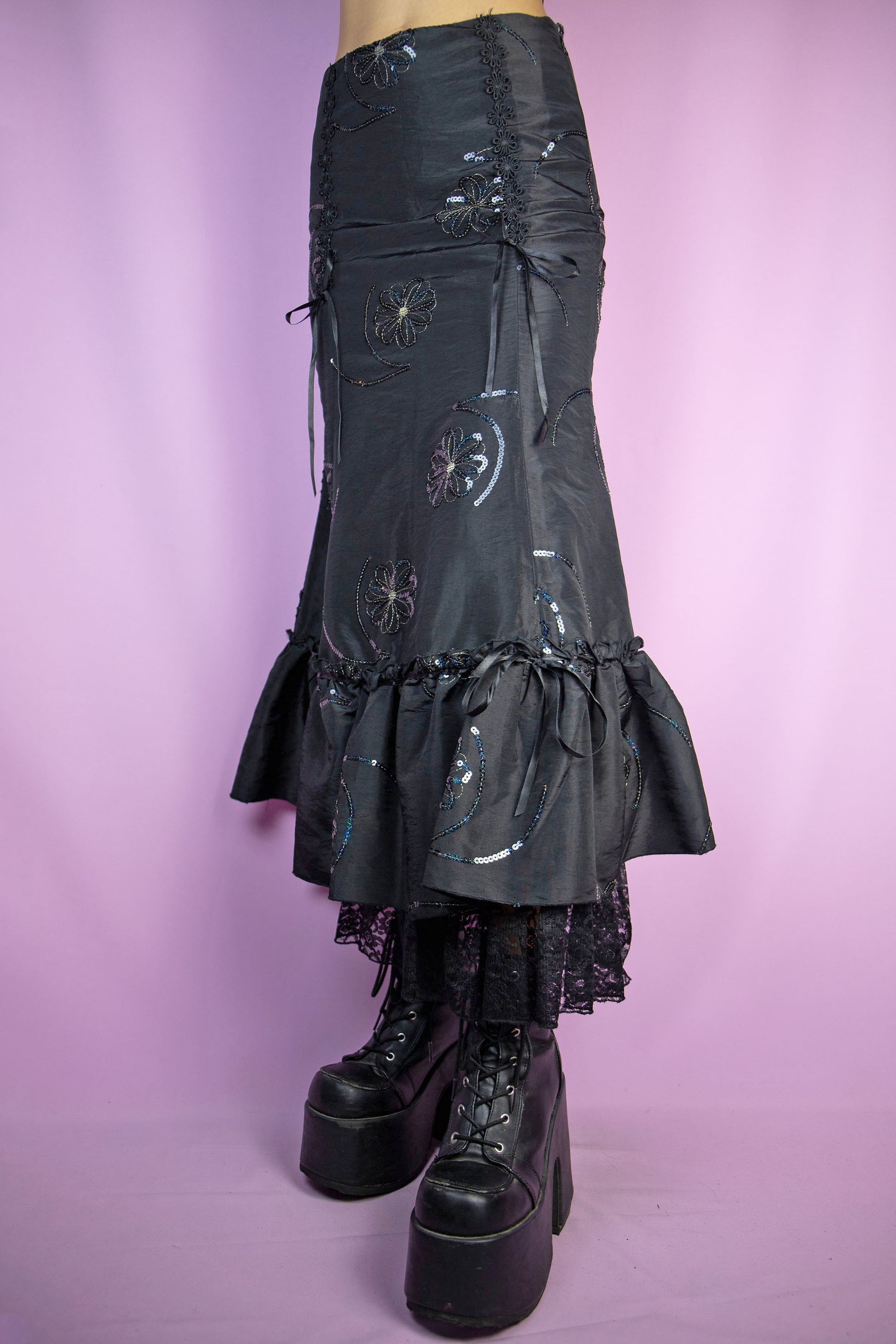 The Vintage 90s Black Trumpet Midi Skirt is an embellished skirt adorned with sequin details, bows, a ruffled hem, and a side zipper closure. Elegant fairy goth 1990s evening party maxi skirt.