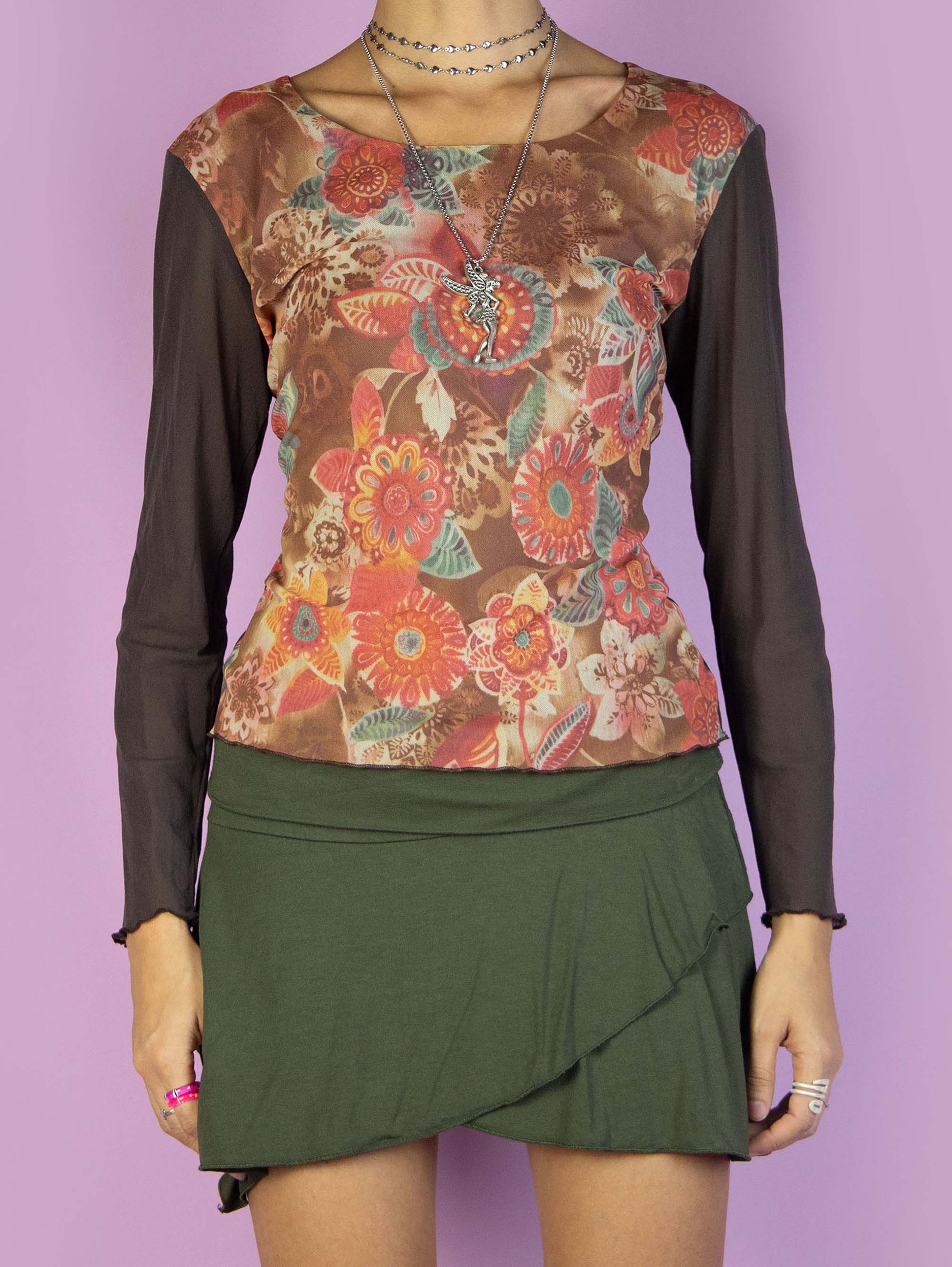 The Y2K Brown Printed Mesh Top is a vintage 2000s long-sleeved, semi-sheer shirt featuring a multicolored abstract floral graphic pattern on the front. This casual top is perfect for everyday outfits.