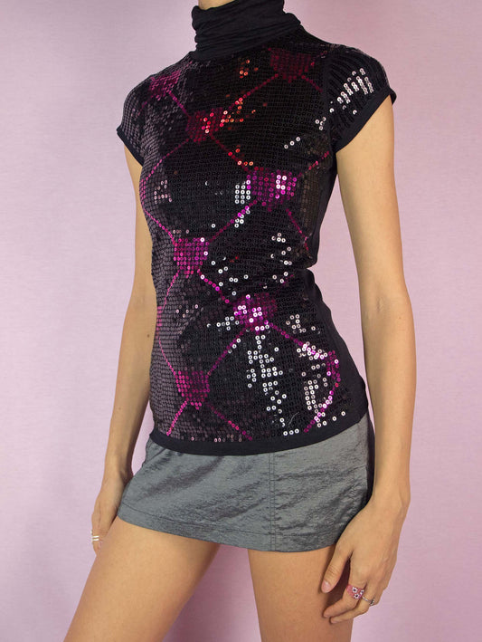 The Y2K Black Sequin Turtleneck Top is a vintage 2000s short-sleeved shirt with a high neckline, adorned with black and pink sequins arranged in a heart pattern. Perfect for a party or a night out.