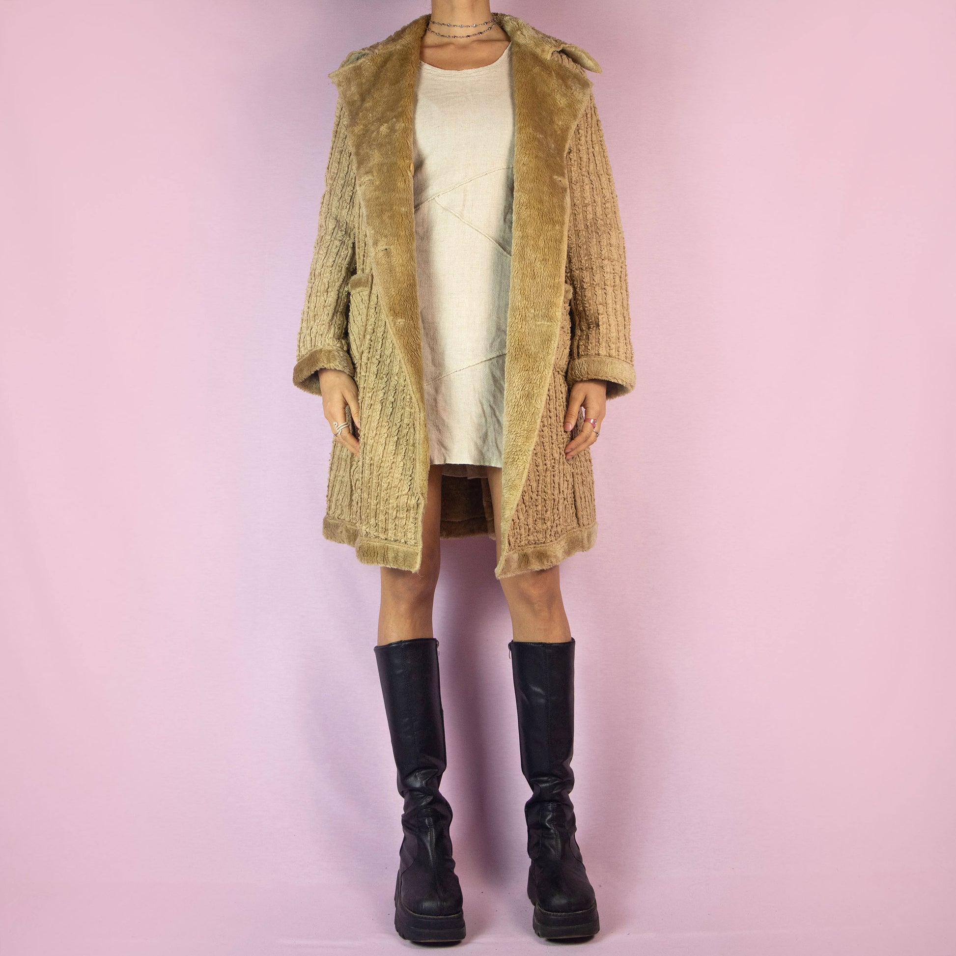 The Y2K Beige Faux Fur Long Coat is a vintage 2000s piece featuring a textured ribbed exterior with a plush faux fur lining throughout. This casual overcoat has a double-breasted button closure, faux fur-trimmed collar, cuffs, and hem, as well as front pockets. Perfect for keeping cozy during casual winter outings.