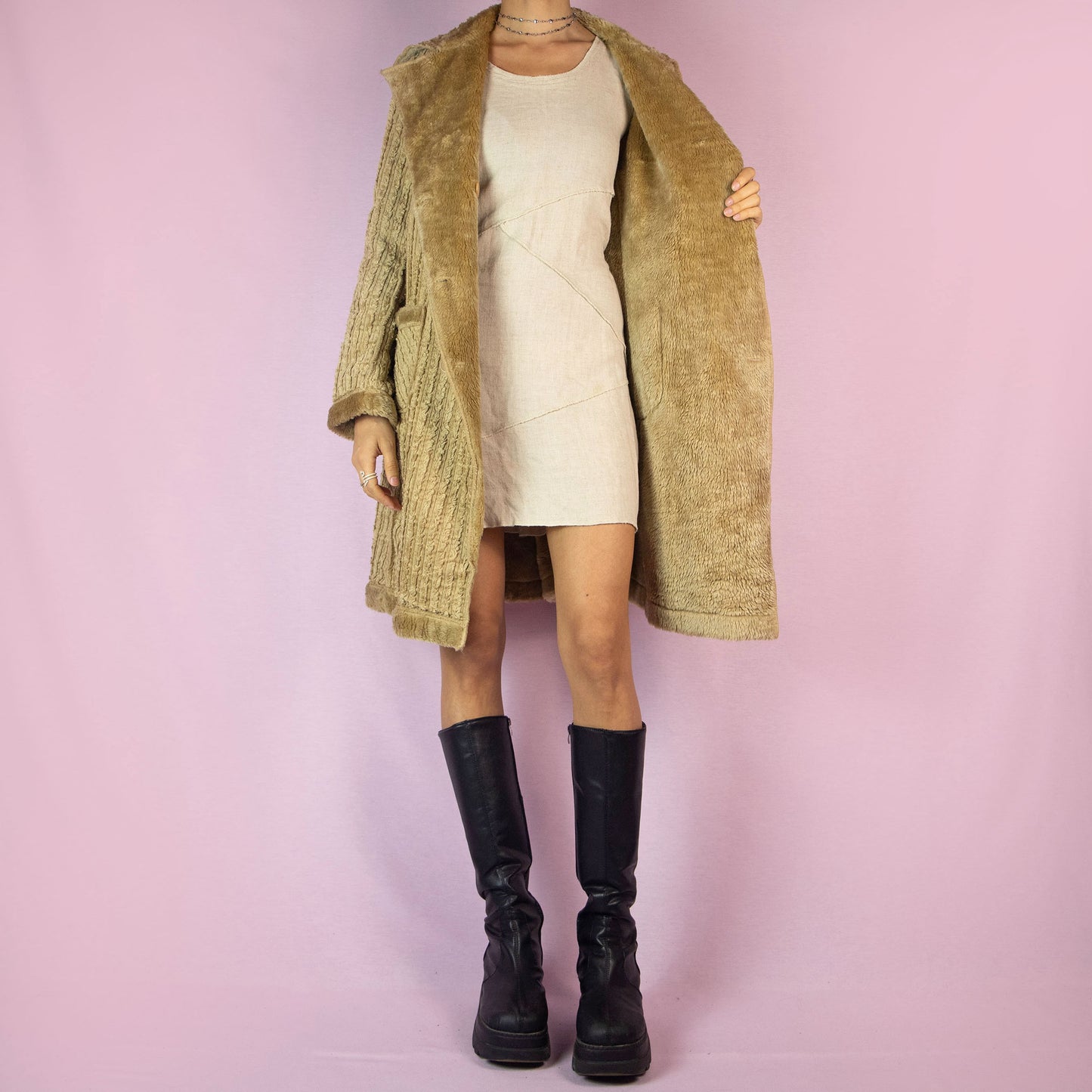 The Y2K Beige Faux Fur Long Coat is a vintage 2000s piece featuring a textured ribbed exterior with a plush faux fur lining throughout. This casual overcoat has a double-breasted button closure, faux fur-trimmed collar, cuffs, and hem, as well as front pockets. Perfect for keeping cozy during casual winter outings.