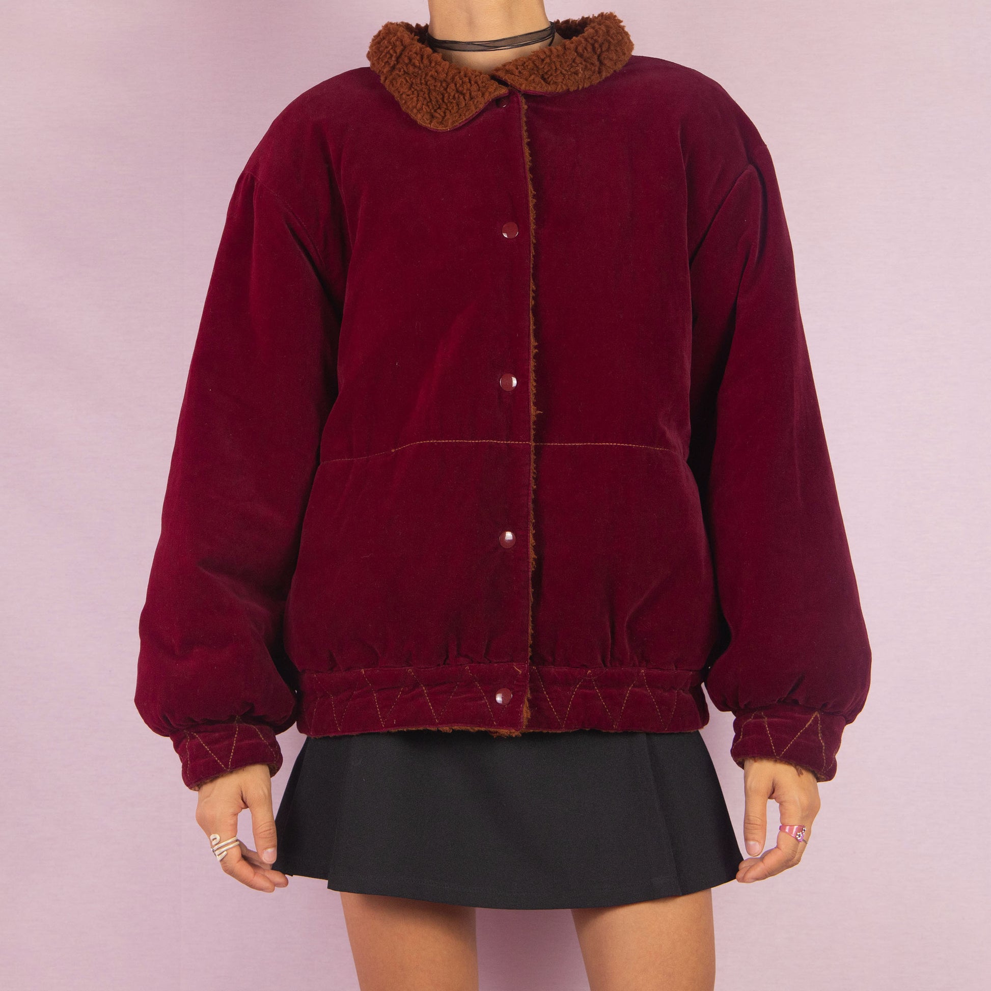 The Vintage 90s Red Velvet Bomber Jacket is a striking piece with a deep red velvet exterior featuring a contrasting brown faux shearling collar and inner lining. It includes snap button closures. Perfect for casual winter days or adding a bold touch to any outfit. Made in Italy.