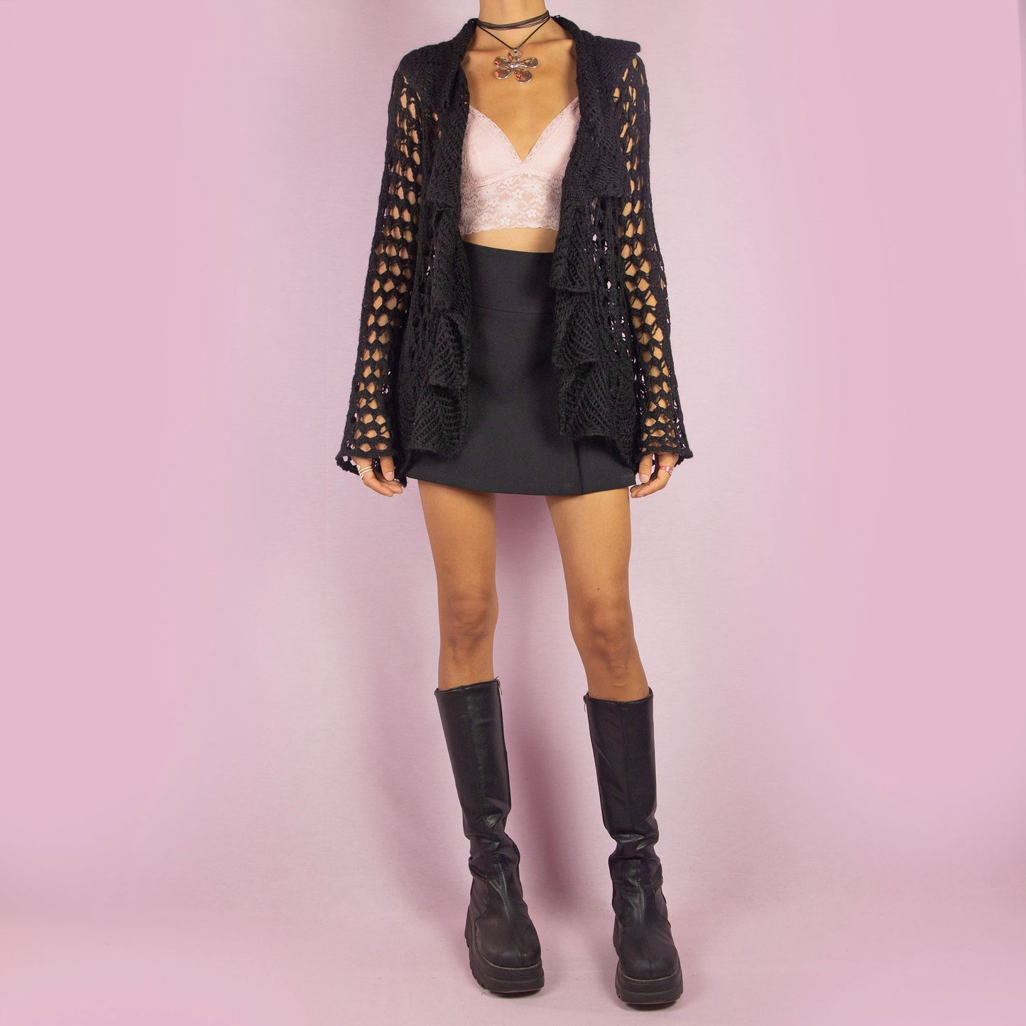The Y2K Black Ruffle Crochet Cardigan is a vintage 2000s piece featuring an open-knit crochet design with an open front, flared sleeves, and a flowy ruffled hem. This lightweight cardigan is perfect for layering, adding a boho touch to any casual or party outfit.