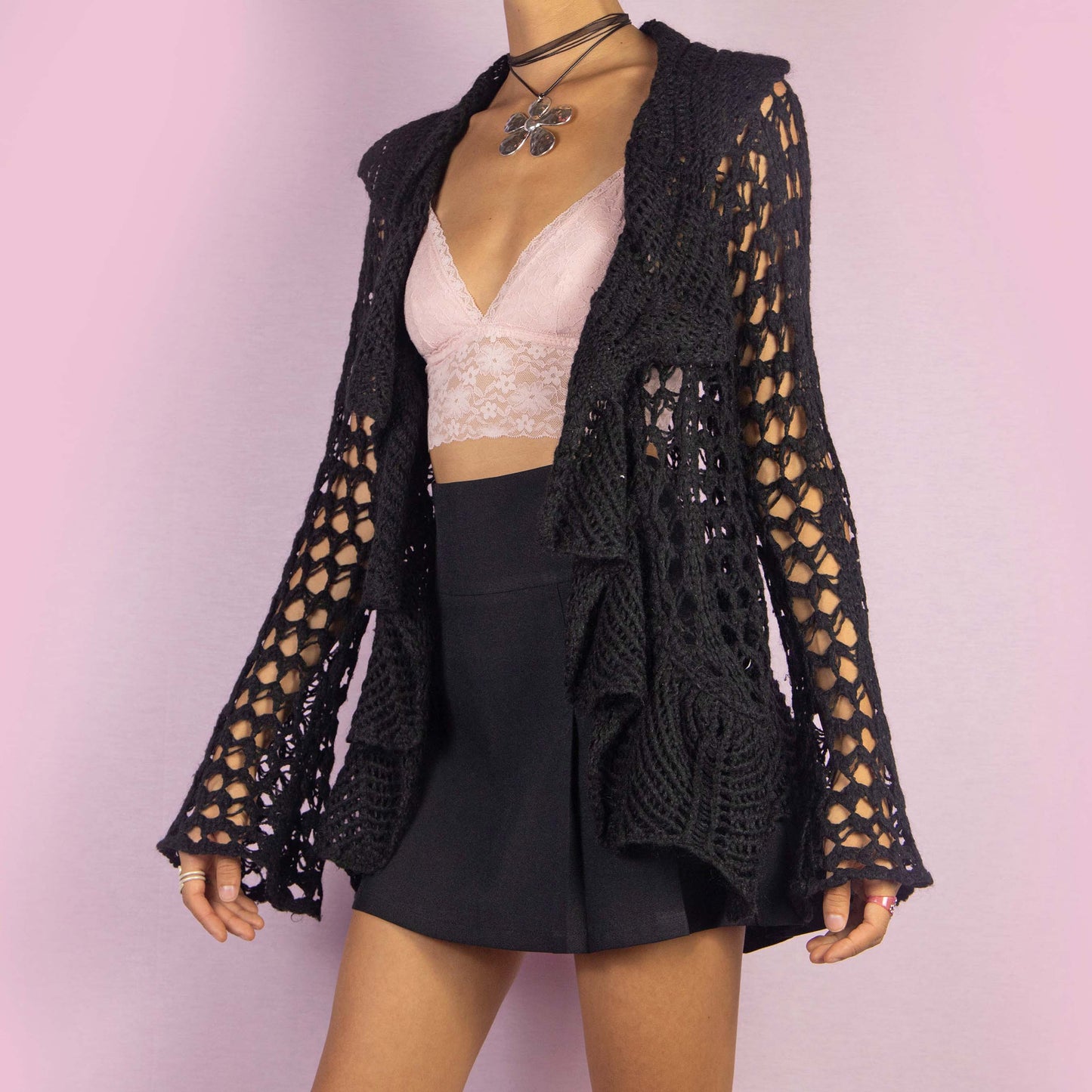 The Y2K Black Ruffle Crochet Cardigan is a vintage 2000s piece featuring an open-knit crochet design with an open front, flared sleeves, and a flowy ruffled hem. This lightweight cardigan is perfect for layering, adding a boho touch to any casual or party outfit.