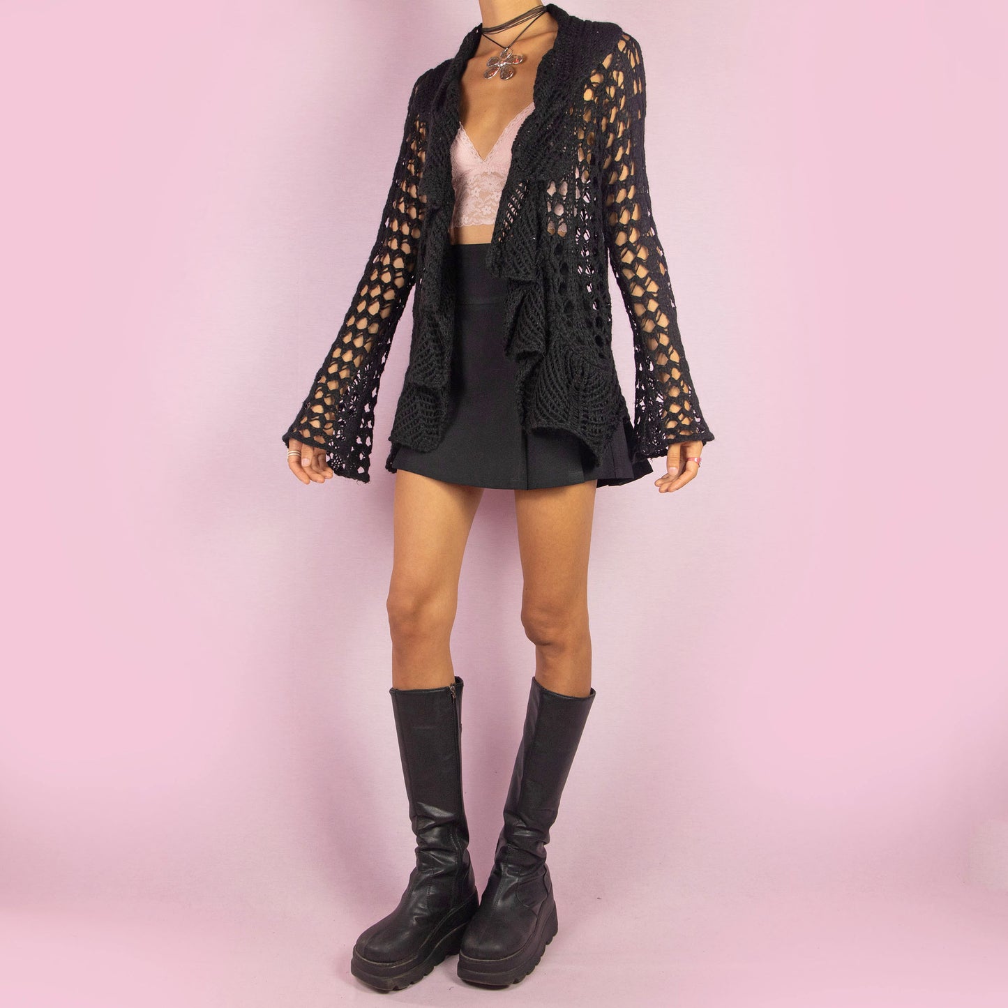 The Y2K Black Ruffle Crochet Cardigan is a vintage 2000s piece featuring an open-knit crochet design with an open front, flared sleeves, and a flowy ruffled hem. This lightweight cardigan is perfect for layering, adding a boho touch to any casual or party outfit.