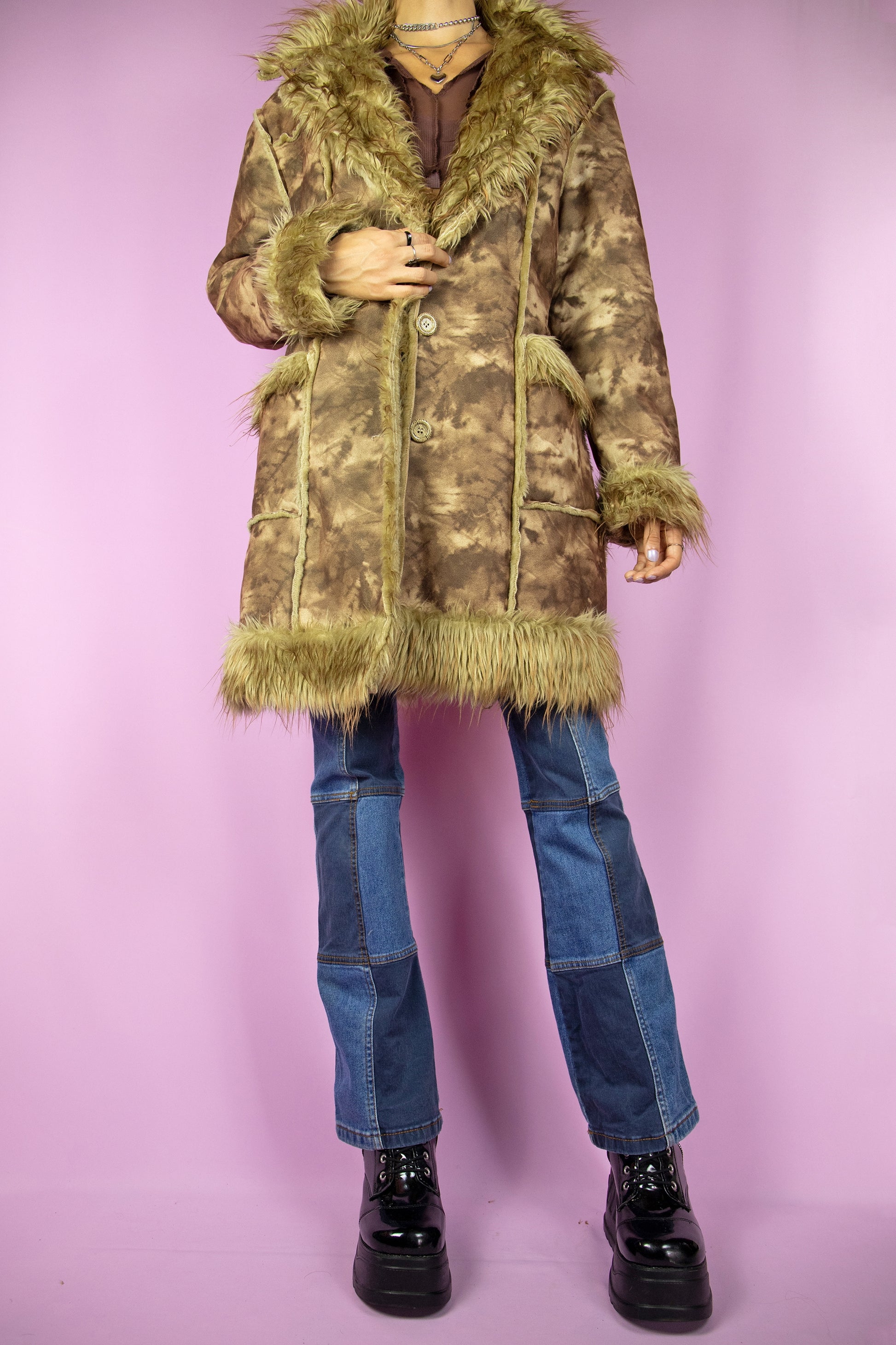 The Vintage Y2K Brown Penny Lane Coat is a long coat showcasing a brown tie-dye print, faux fur collar and cuffs, pockets, and button closure, creating an iconic afghan style winter coat from the 2000s. This stunning coat serves as a distinctive expression of boho fairy grunge fashion, making it a noteworthy statement piece.