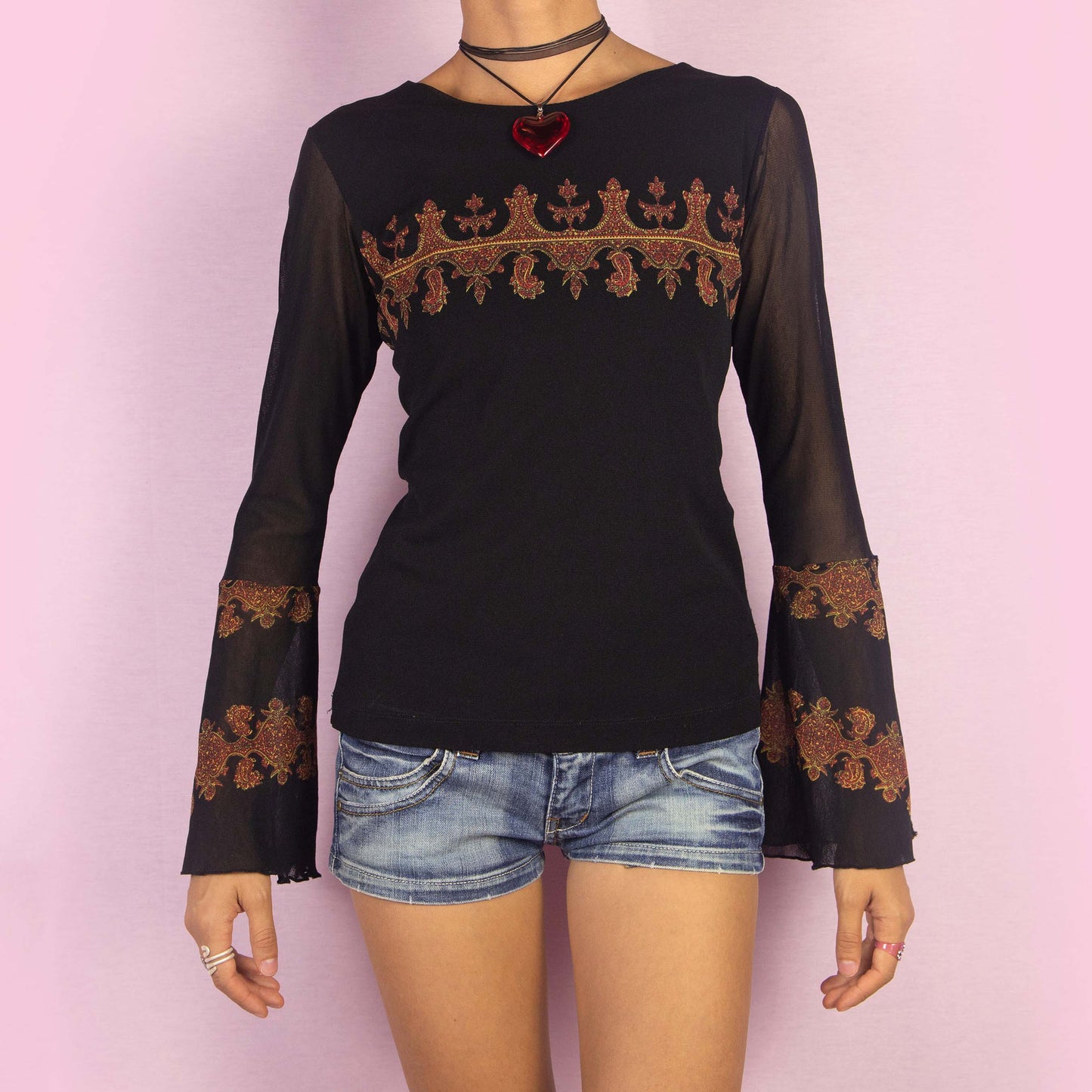 The Y2K Black Mesh Bell Sleeve Top is a vintage 2000s piece featuring a paisley-inspired print with baroque-style elements in warm hues across the chest and bell sleeves. Made from a semi-sheer mesh fabric, this top includes dramatic slit flared sleeves. Perfect for whimsical evening events.