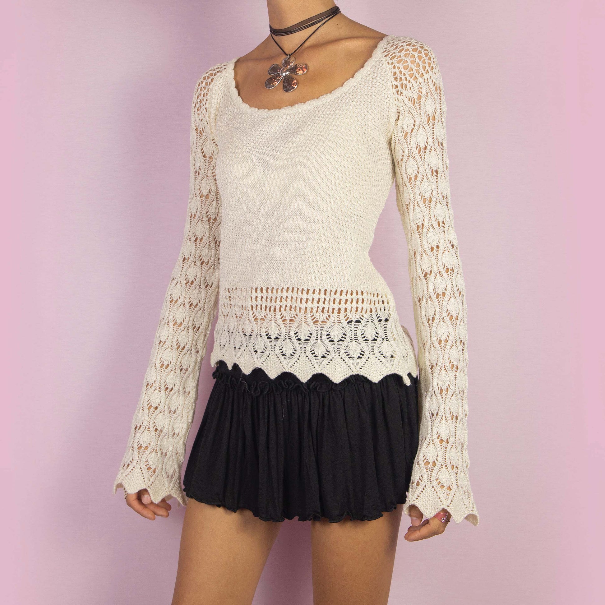 The Y2K Cream Bell Sleeve Sweater is a vintage 2000s white stretchy pullover featuring an intricate open-knit crochet design and long flared sleeves. Perfect for casual autumn days.