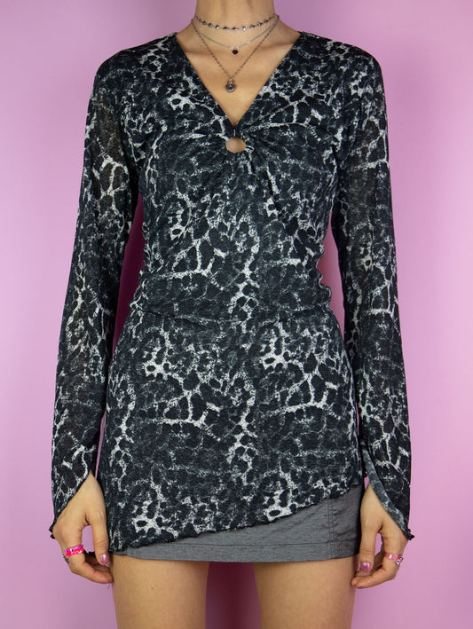 The Y2K Printed Mesh Asymmetric Top is a vintage 2000s black, gray, and white semi-sheer blouse featuring a bold leopard animal print, a ruched front with o-ring details and an asymmetric design. Perfect for any party or night out ensemble.