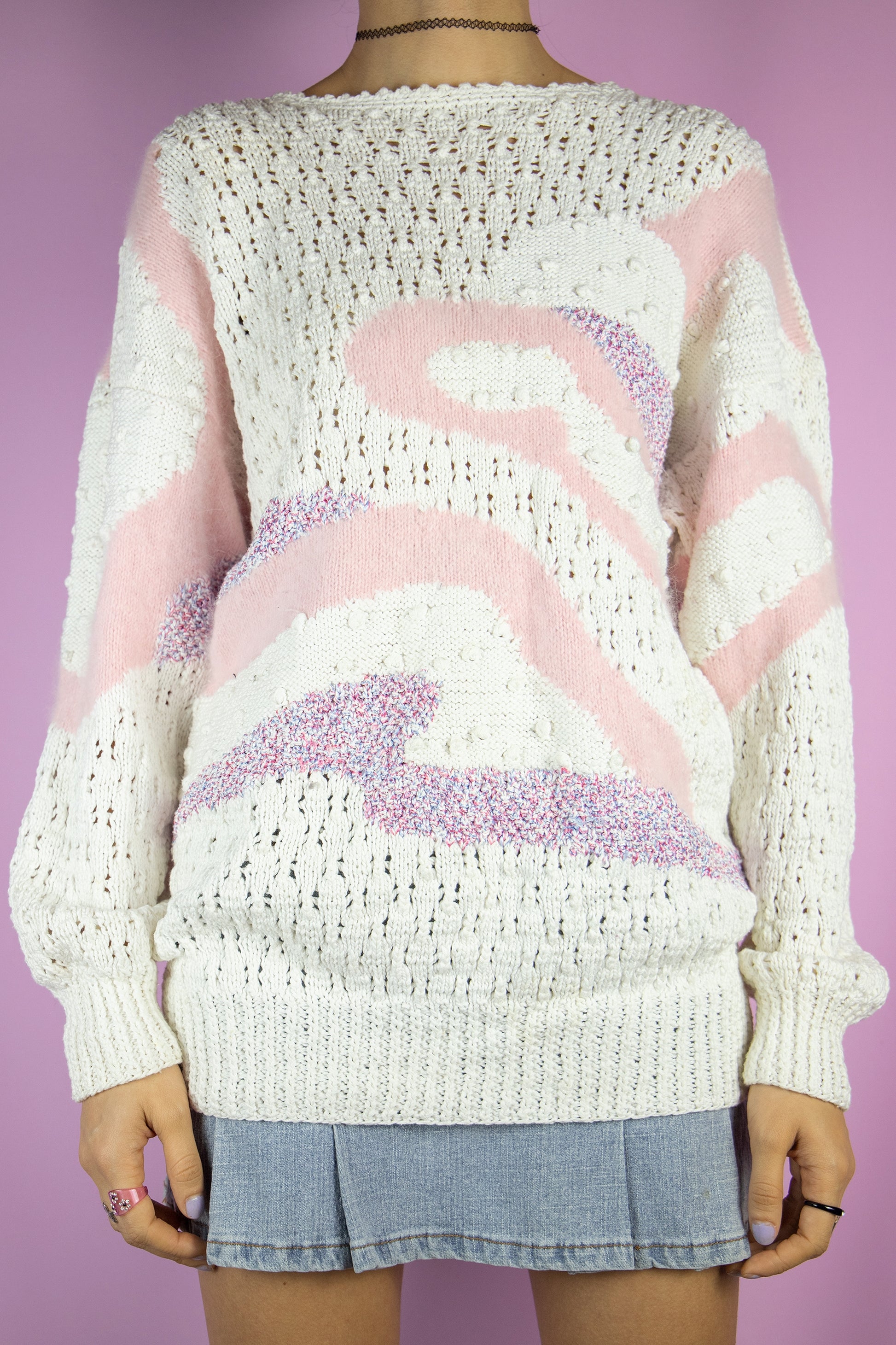 The Vintage 80s Retro White Knit Sweater is an elegant pullover featuring an abstract pattern complemented by pink multicolor details. This chic sweater is perfect for any casual winter outfit.