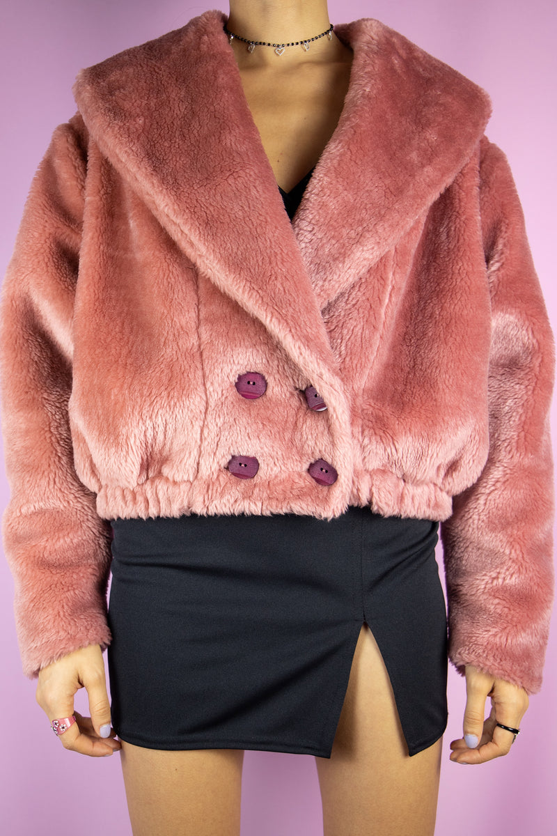 The Vintage 90s Pink Faux Fur Jacket is a pastel dusty pink faux fur jacket with a collar, buttons, pockets and elasticated waist. Romantic boho retro 1990s winter statement coat.