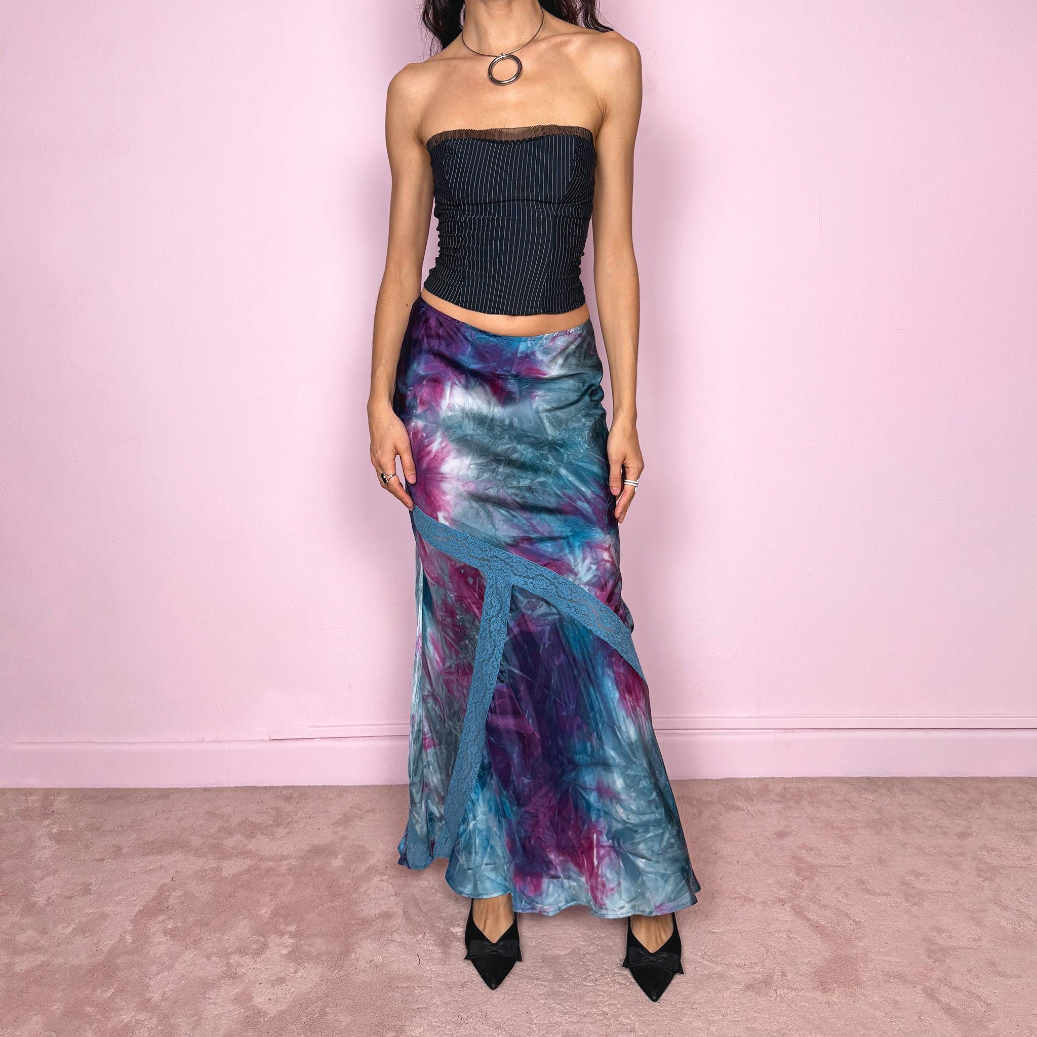 Vintage 2000s blue and purple tie dye midi skirt in a flowy bias cut slip silhouette with a soft, draped fit. Features a unique asymmetric lace panel detail, back zip closure, and fluid movement. From Kenzo Jeans, the brand’s early 2000s diffusion line known for its playful prints and fluid, feminine silhouettes. Perfect for summer, arty gallery girl looks, or vacation styling, a bold yet wearable statement piece. Can be worn mid rise for size XS or high waisted for size S.
