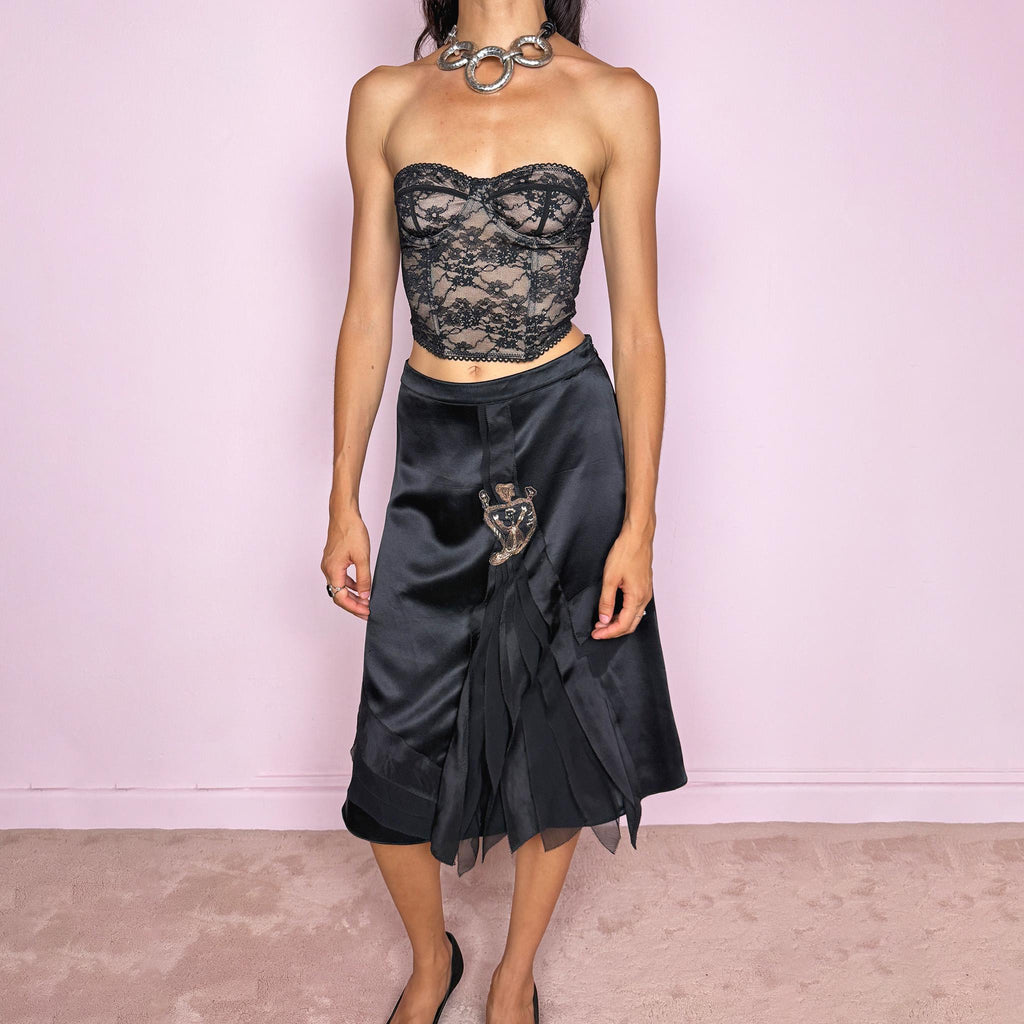 Vintage 2000s Kenzo black midi skirt crafted from 100% silk in a deep black satin finish, designed with a side zip closure and a structured no-stretch fit. It features a dramatic front detail with layered sheer pleated silk panels and an embroidered appliqué motif. A refined designer piece with a dark romantic evening feel, balancing minimal black silk with ornate Kenzo detailing. Can be worn high-waisted for size S, or slightly lower on the waist for XS and XXS. Excellent vintage condition.