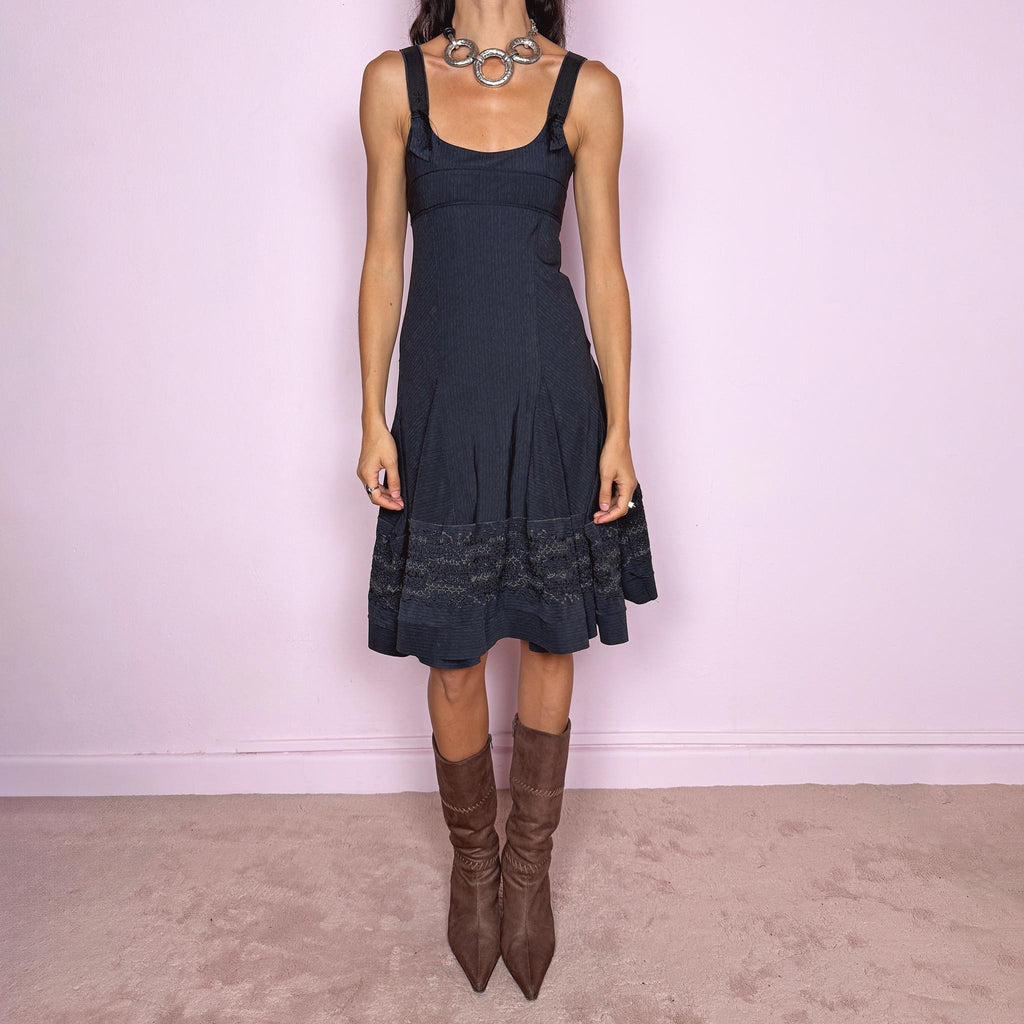 Vintage 2000s black midi dress by French label Marithé + François Girbaud, featuring a fitted sleeveless bodice with a scoop neckline and curved seam construction through the torso. The fabric has a subtle micro-pinstripe texture, while the silhouette flares from the hips into a structured A-line skirt with embroidered details. Made from a stretchy blend of 72% polyamide and 28% elastane. Excellent vintage condition.