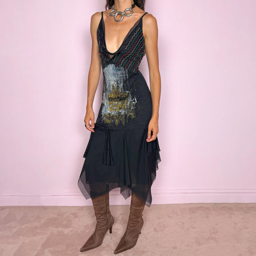 Vintage 2000s Save The Queen dress with semi-sheer mesh details and a sculptural asymmetric silhouette. Designed with thin straps, a deep V neckline, a fitted embroidered bodice with colorful zigzag stitching and a striking architectural graphic print across the front, falling into a layered black skirt with uneven sheer mesh panels and soft draped movement. A rare Italian Y2K statement piece with a dark romantic art-to-wear feel, balancing gothic fairycore