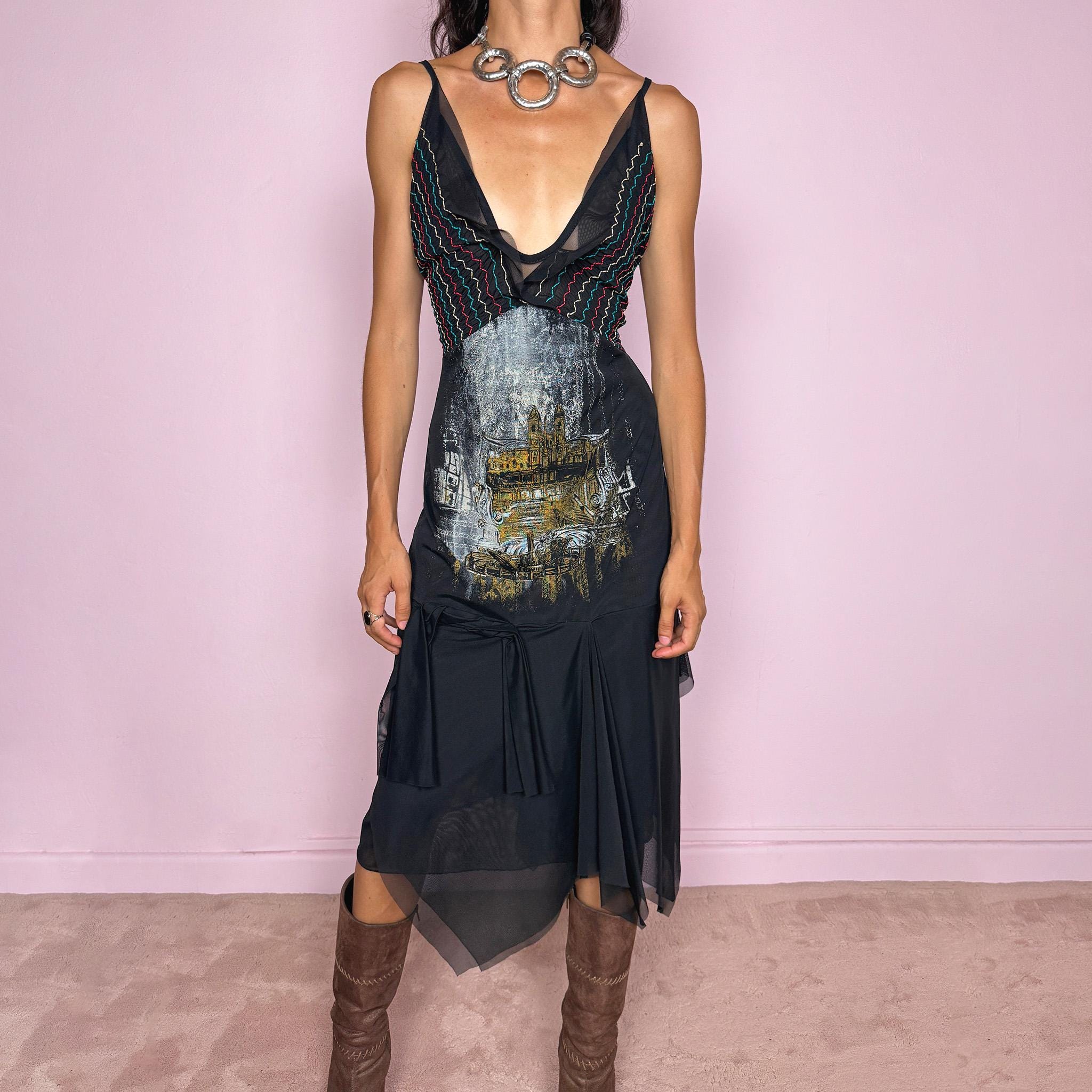 Vintage 2000s Save The Queen dress with semi-sheer mesh details and a sculptural asymmetric silhouette. Designed with thin straps, a deep V neckline, a fitted embroidered bodice with colorful zigzag stitching and a striking architectural graphic print across the front, falling into a layered black skirt with uneven sheer mesh panels and soft draped movement. A rare Italian Y2K statement piece with a dark romantic art-to-wear feel, balancing gothic fairycore