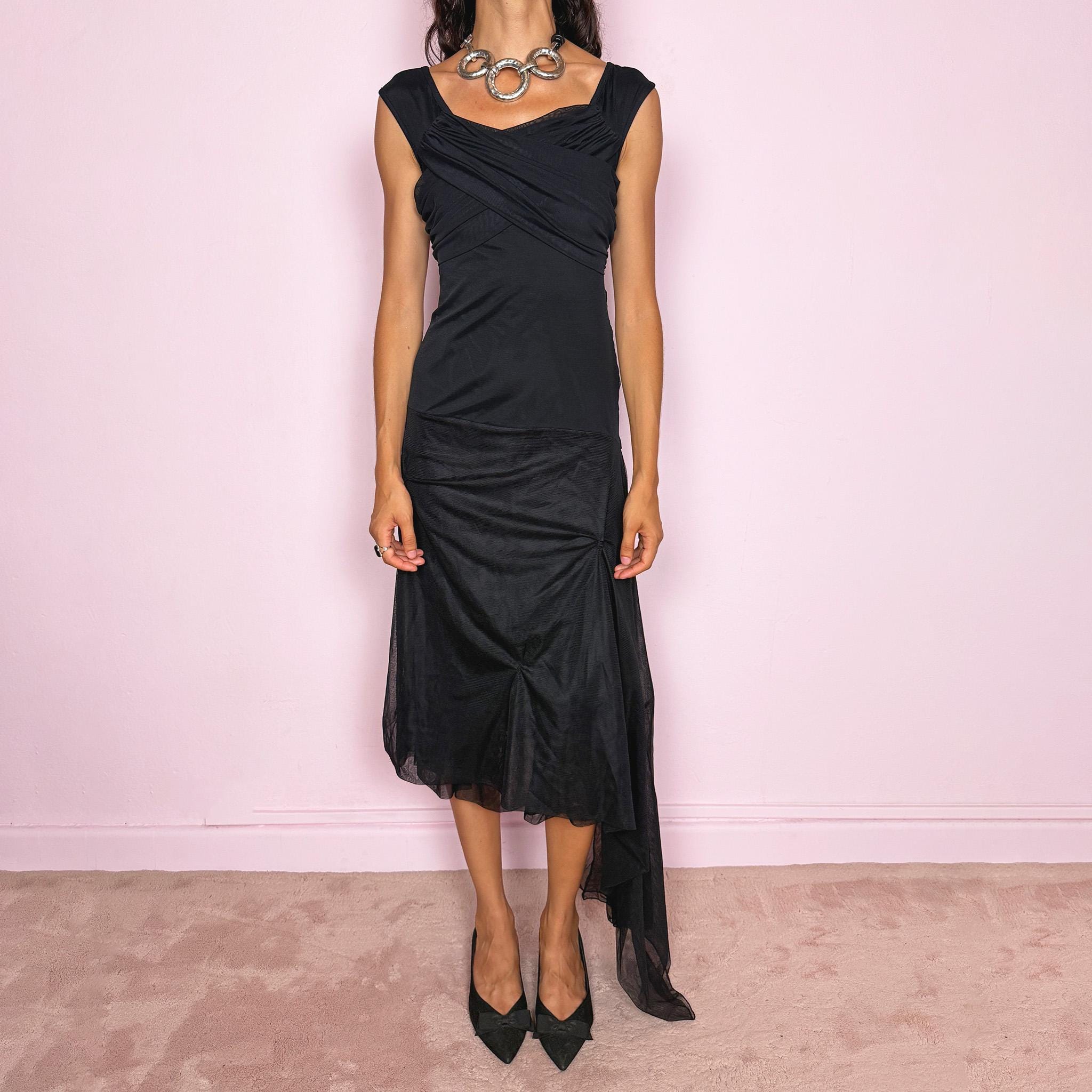 Vintage 2000s Save The Queen black midi dress with semi-sheer mesh layering and a sculptural asymmetric silhouette. It features a softly draped off-shoulder neckline, short cap sleeves, a fitted stretch body with diagonal ruching through the bust and waist, and an asymmetric layered skirt with sheer mesh panels, gathered details, and a long cascading side drape for dramatic movement. A rare Italian Y2K statement piece with a dark romantic evening feel, perfect for elegant parties and occasions.