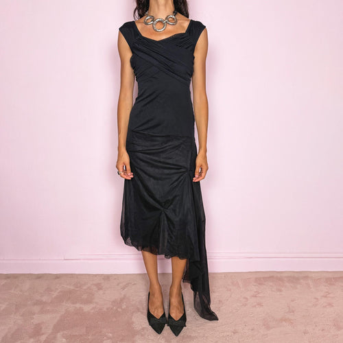 Vintage 2000s Save The Queen black midi dress with semi-sheer mesh layering and a sculptural asymmetric silhouette. It features a softly draped off-shoulder neckline, short cap sleeves, a fitted stretch body with diagonal ruching through the bust and waist, and an asymmetric layered skirt with sheer mesh panels, gathered details, and a long cascading side drape for dramatic movement. A rare Italian Y2K statement piece with a dark romantic evening feel, perfect for elegant parties and occasions.