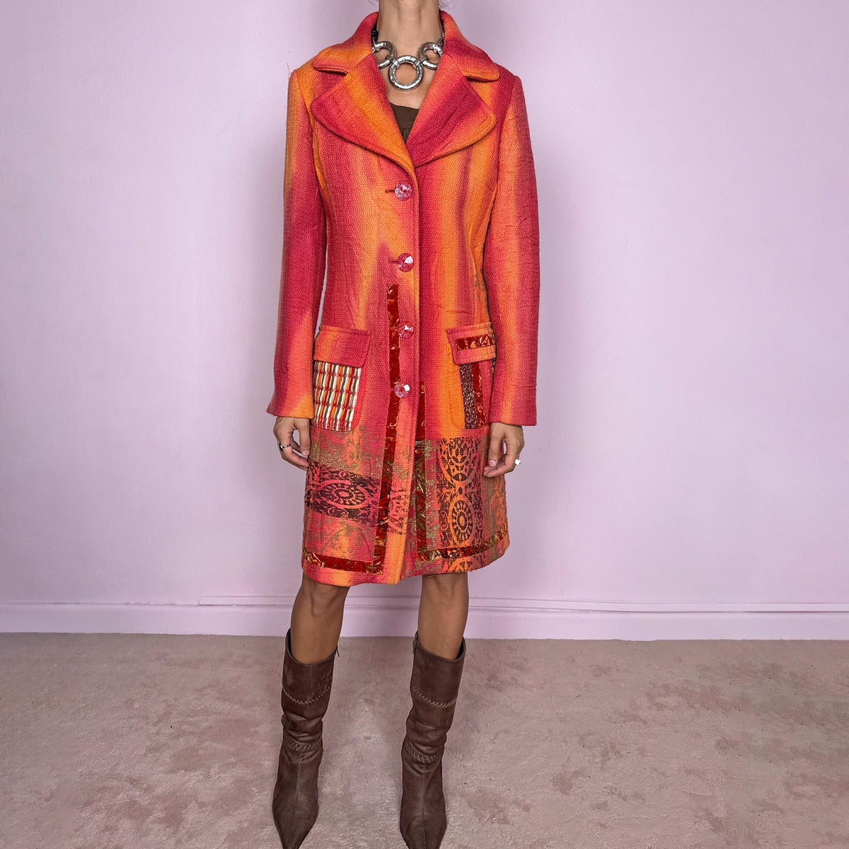 Vintage 2000s statement coat by Italian label Save the Queen, made in Italy from 100% virgin wool. Features a fitted longline silhouette in vivid coral, orange and red tones, with oversized notched lapels, decorative front buttons and contrasting mixed-media patch pockets. The lower section is finished with richly patterned jacquard-style panels, metallic accents and ornamental motifs, creating a highly detailed maximalist construction. Excellent vintage condition.